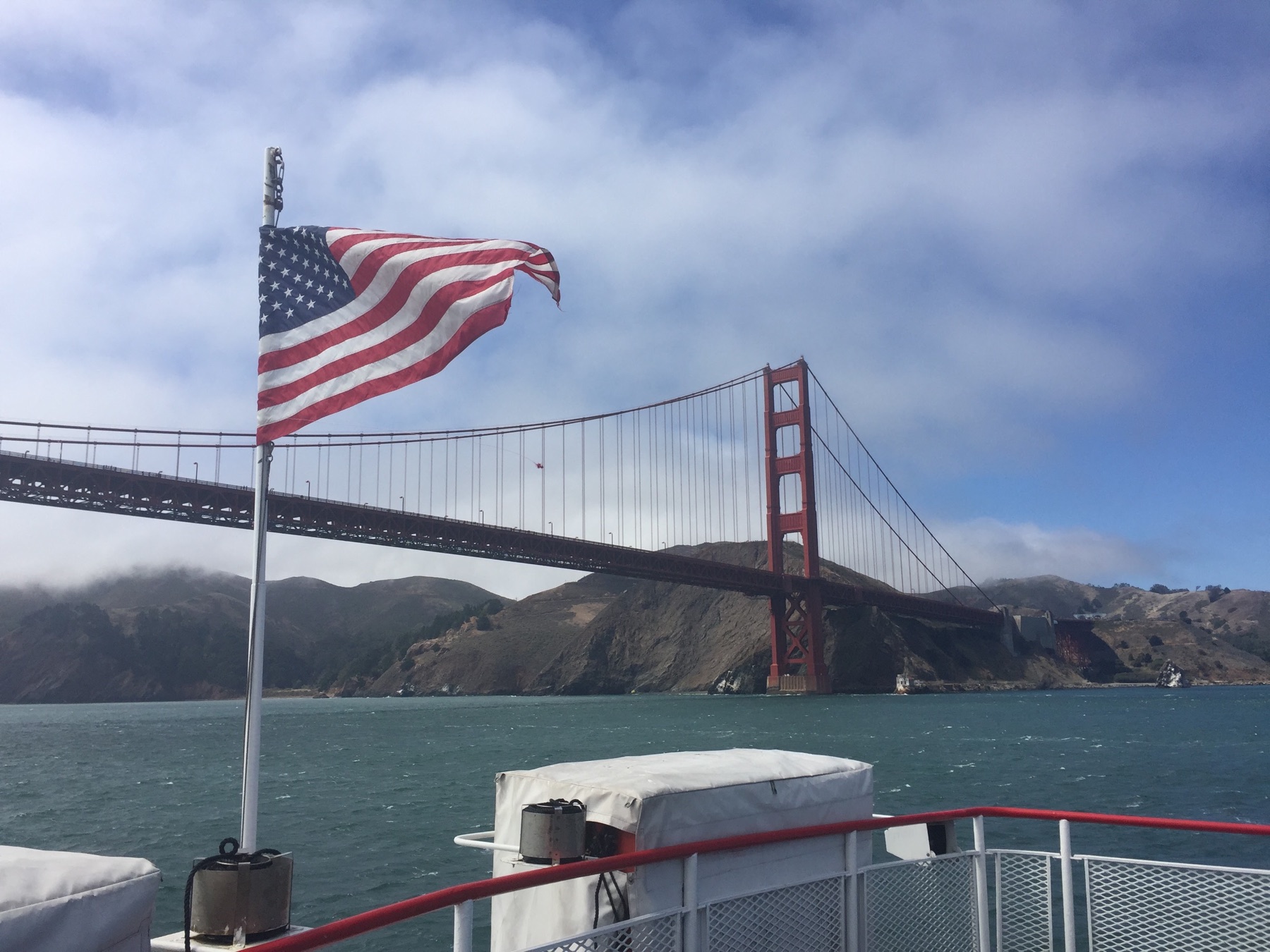 An American flag flying on a bay cruise boat with the Golden Gate Bridge behind it