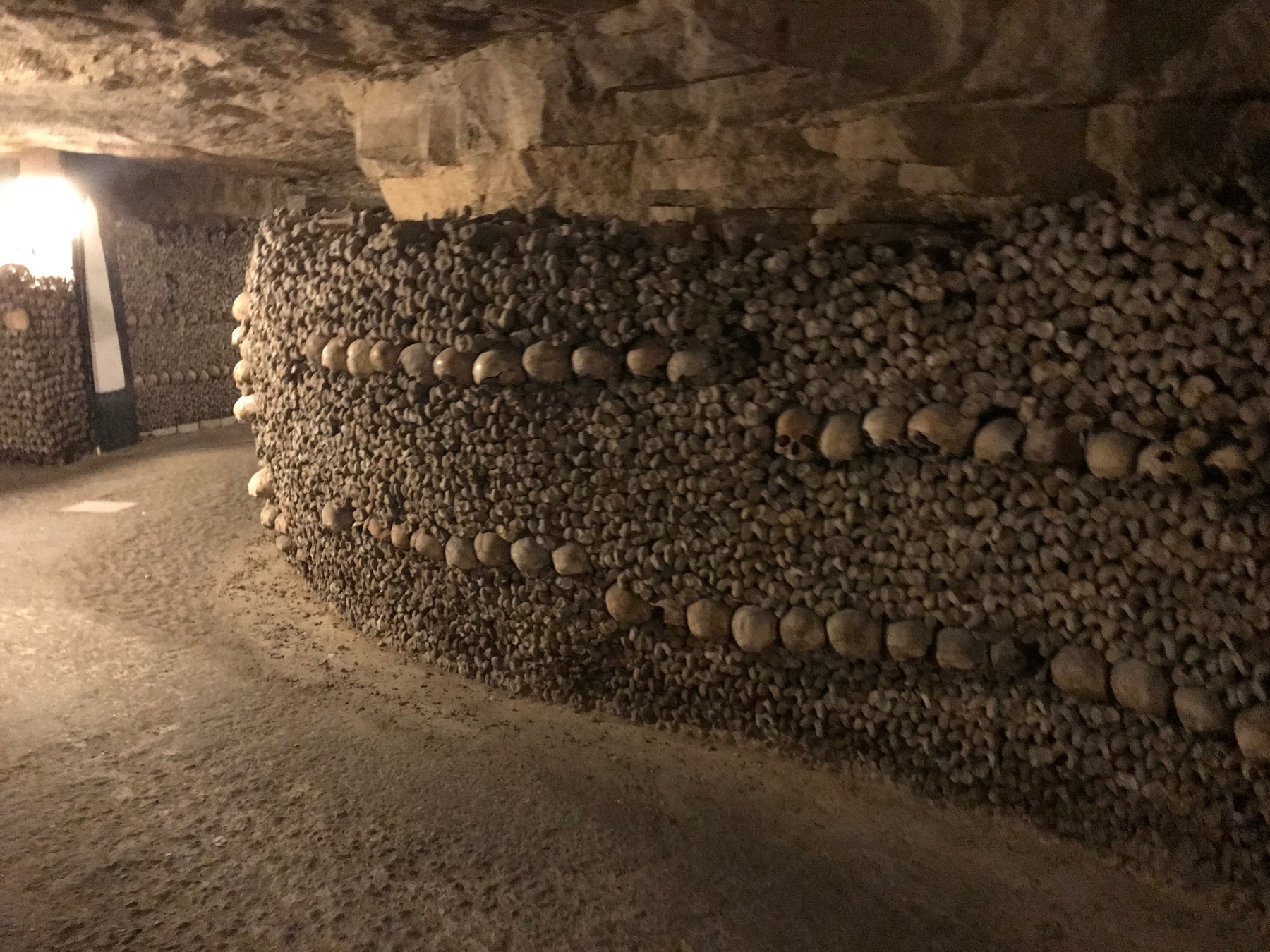 Skulls and bones arranged in long walls inside the Paris Catacombs