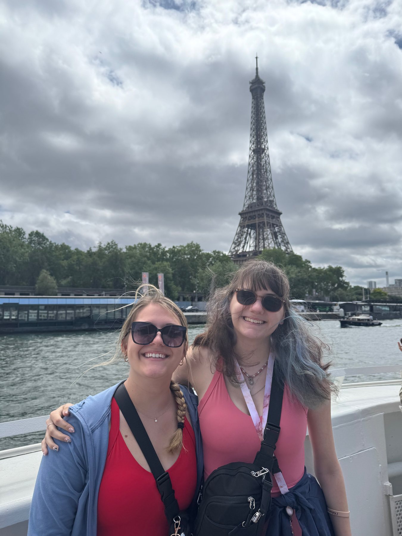 Delaney and Sidney smiling on a Seine cruise with the Eiffel Tower behind them