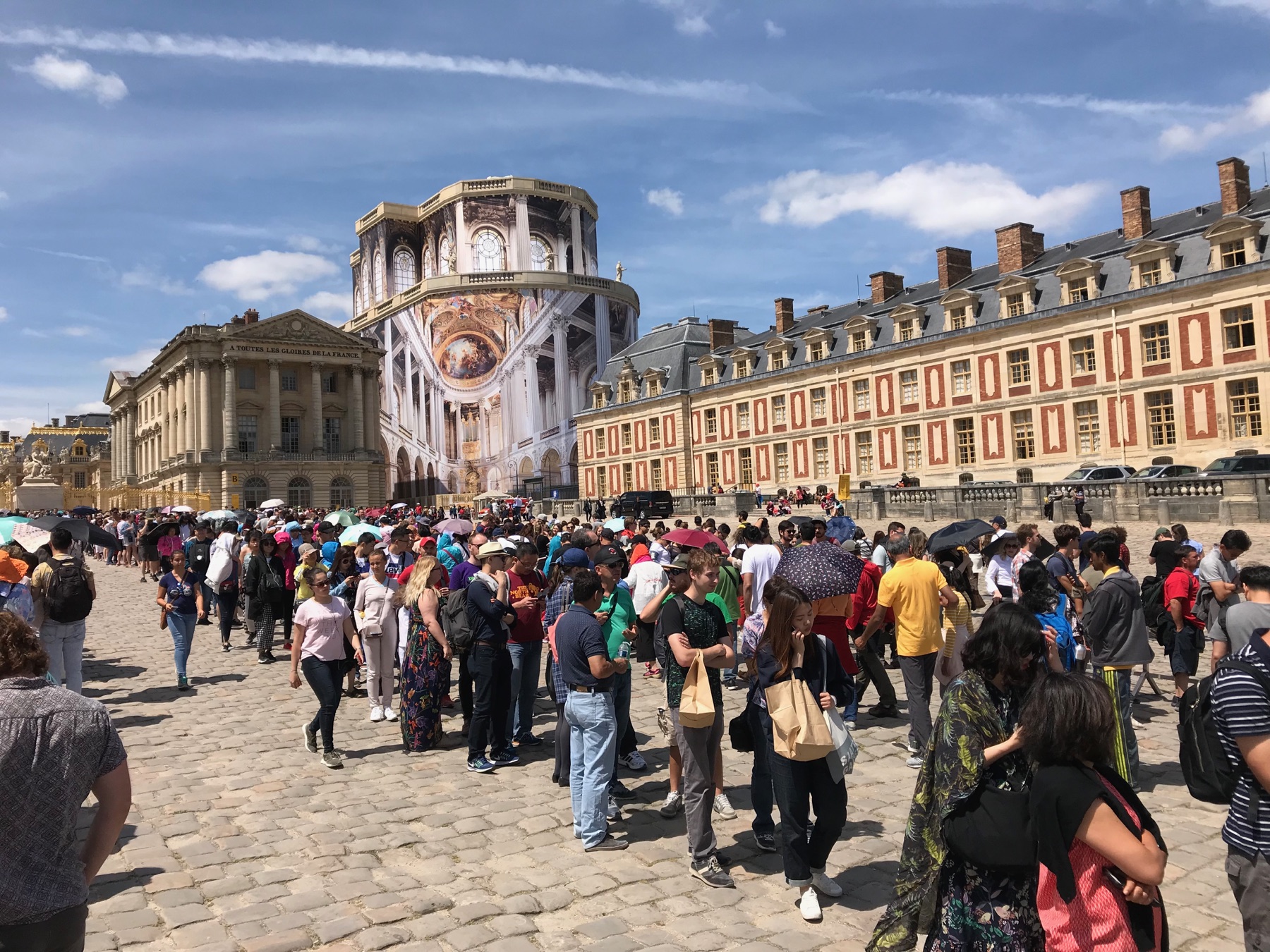 A dense summer entrance line filling the courtyard at the Palace of Versailles