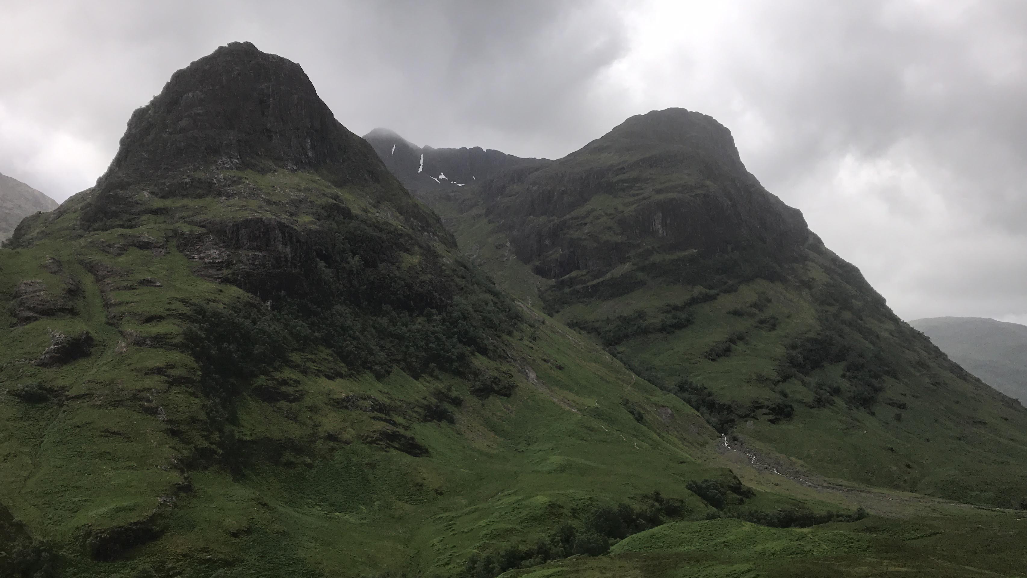 Steep green and rocky slopes of the Three Sisters rising above Glencoe