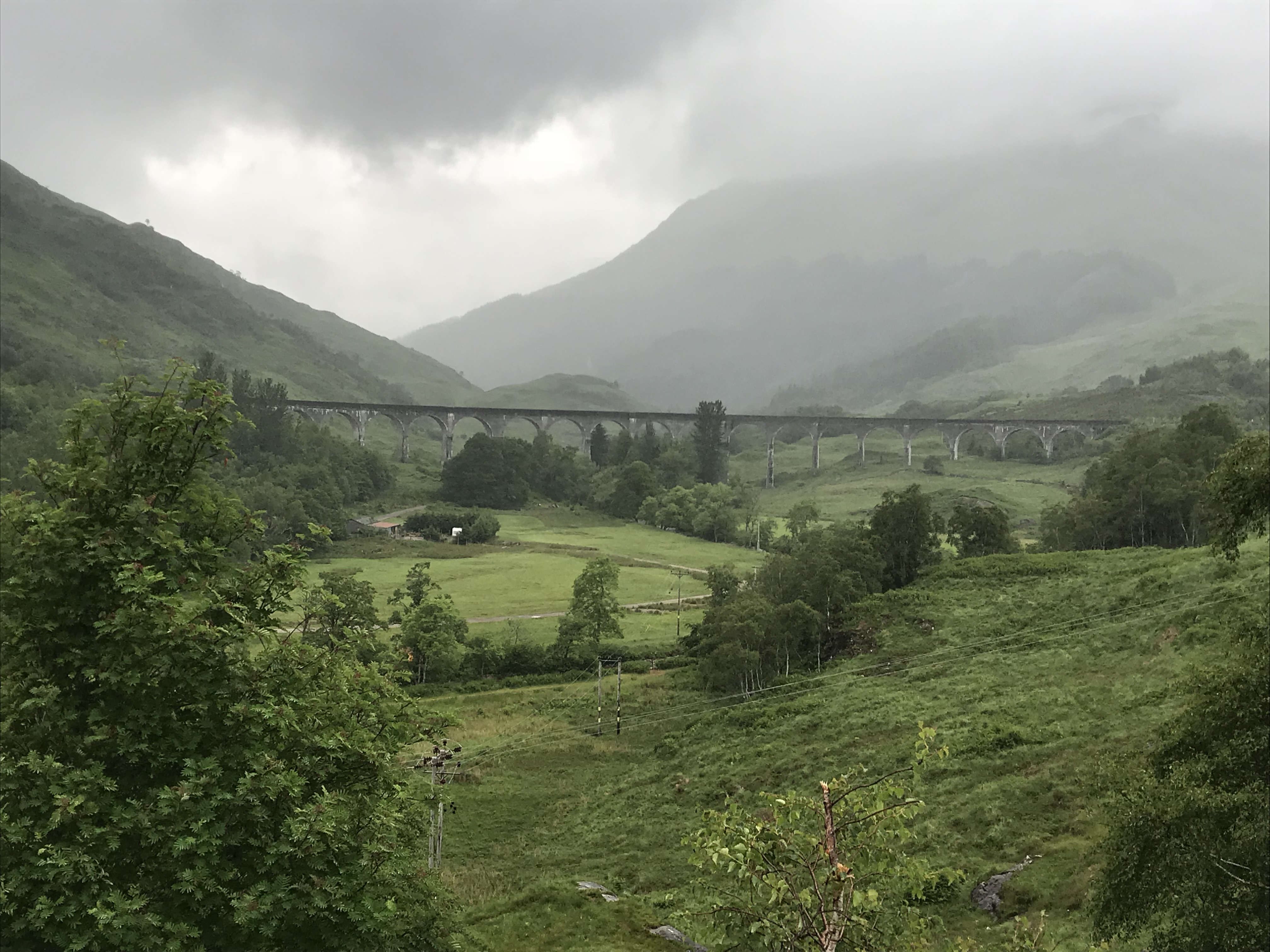 Curving stone railway viaduct spanning the green glen at Glenfinnan