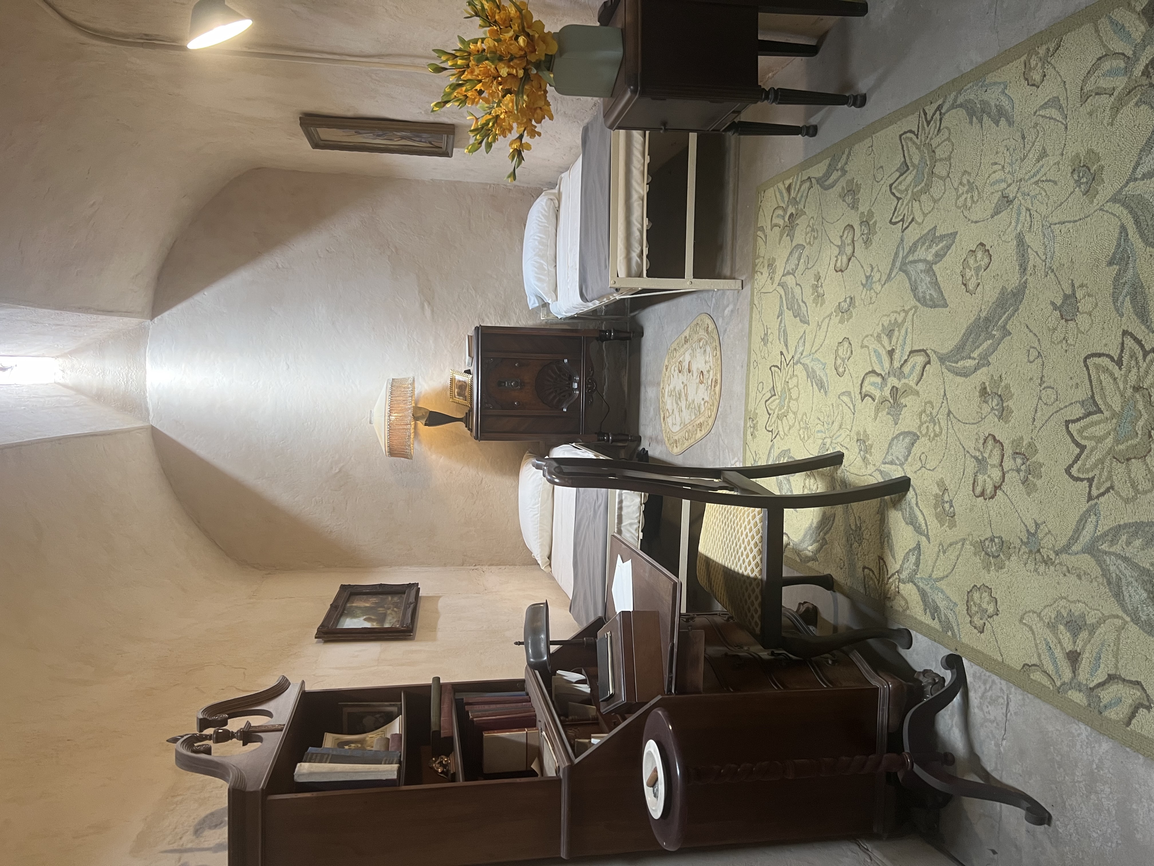 Recreated cell with two beds, wooden furniture, paintings, and a lamp at Eastern State Penitentiary