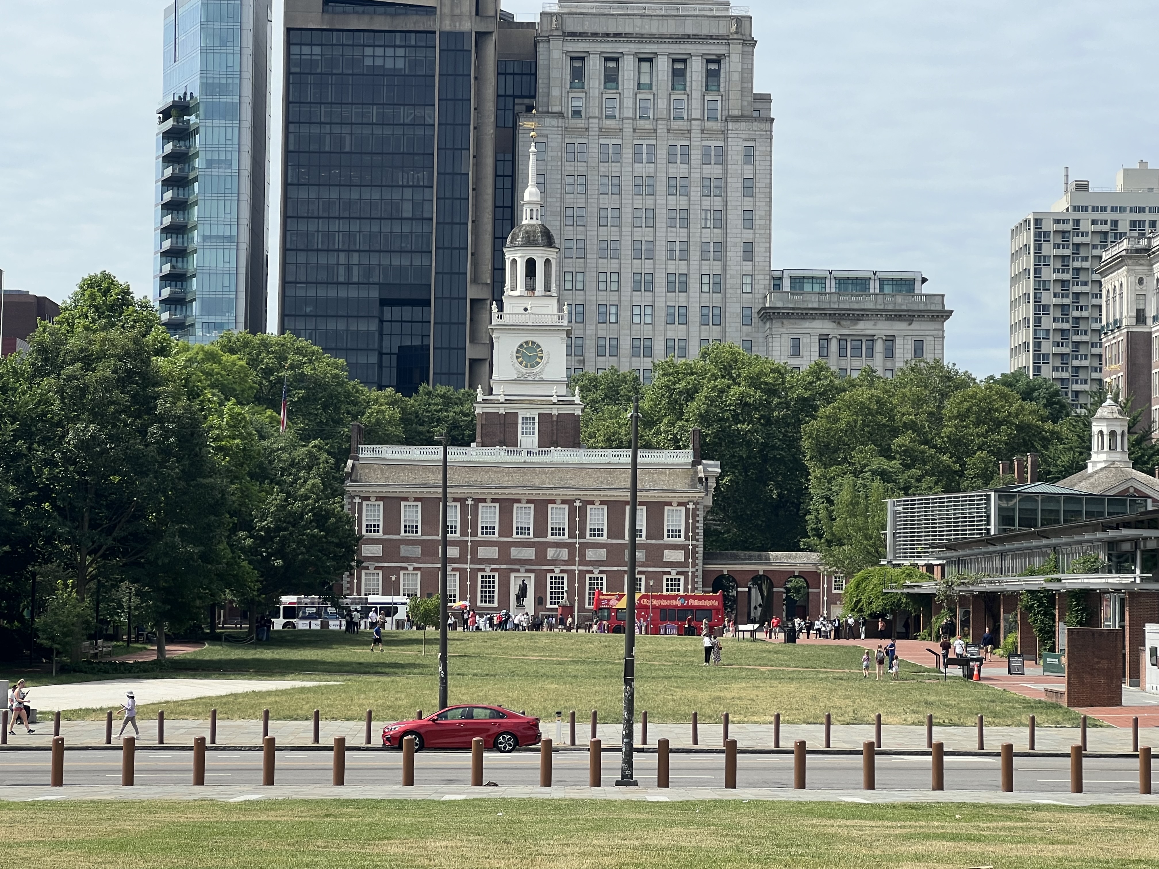 Independence Hall framed by trees and downtown Philadelphia buildings on a sunny day