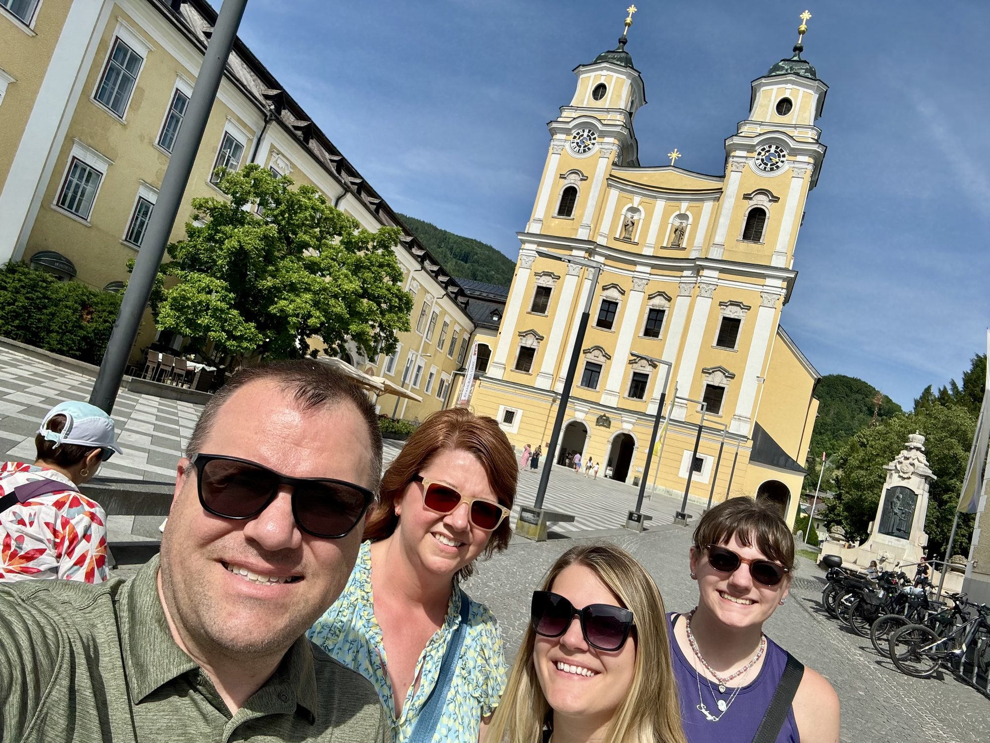 Travelers standing in front of the yellow Basilica of St. Michael in Mondsee