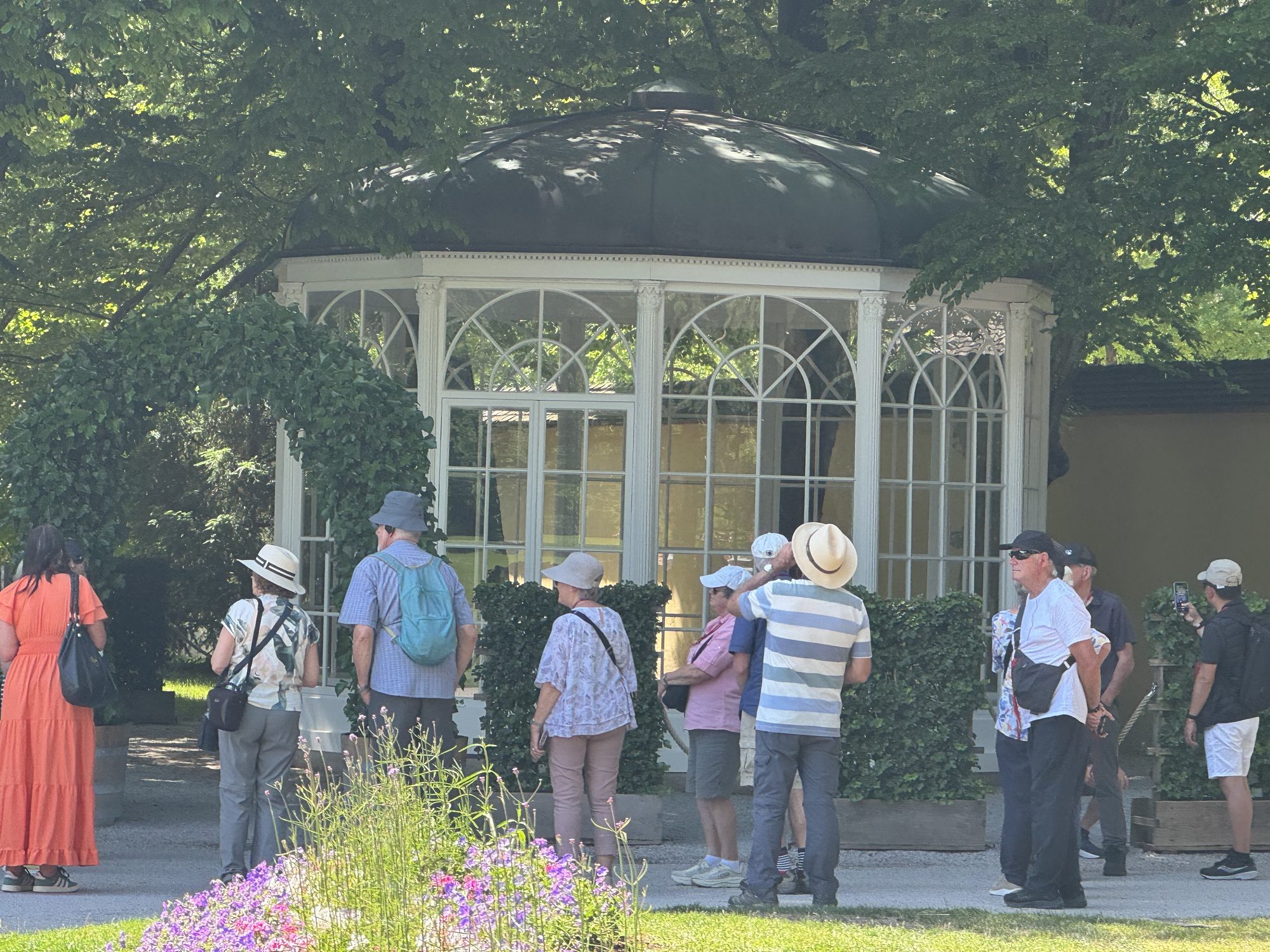 The white glass Sound of Music gazebo among leafy trees at Hellbrunn Palace