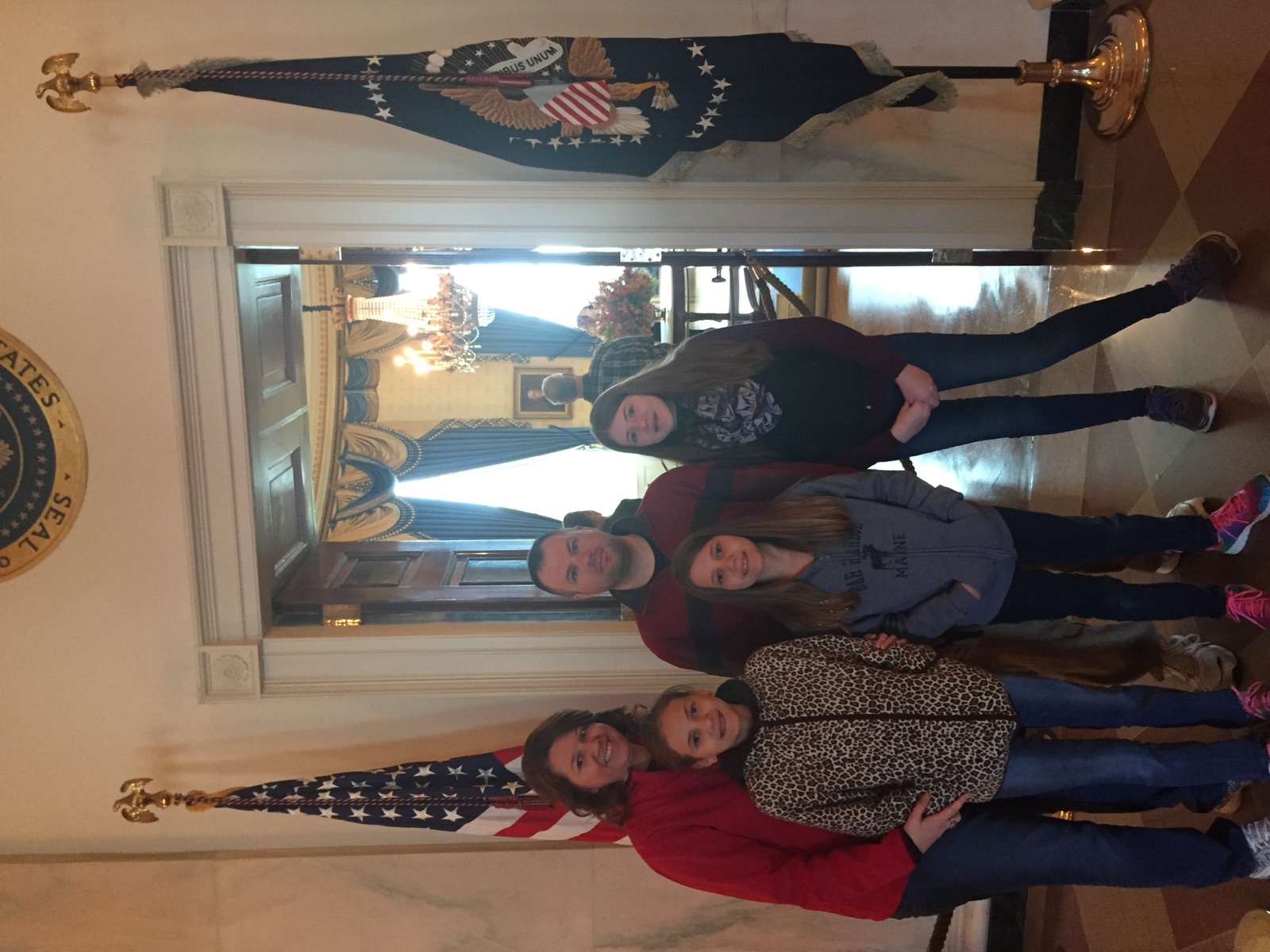 Angela, Brian, and their three daughters standing inside the White House between American and presidential flags
