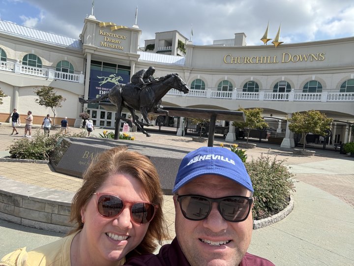 Angela and Brian outside the Kentucky Derby Museum and Churchill Downs, with a racehorse statue behind them