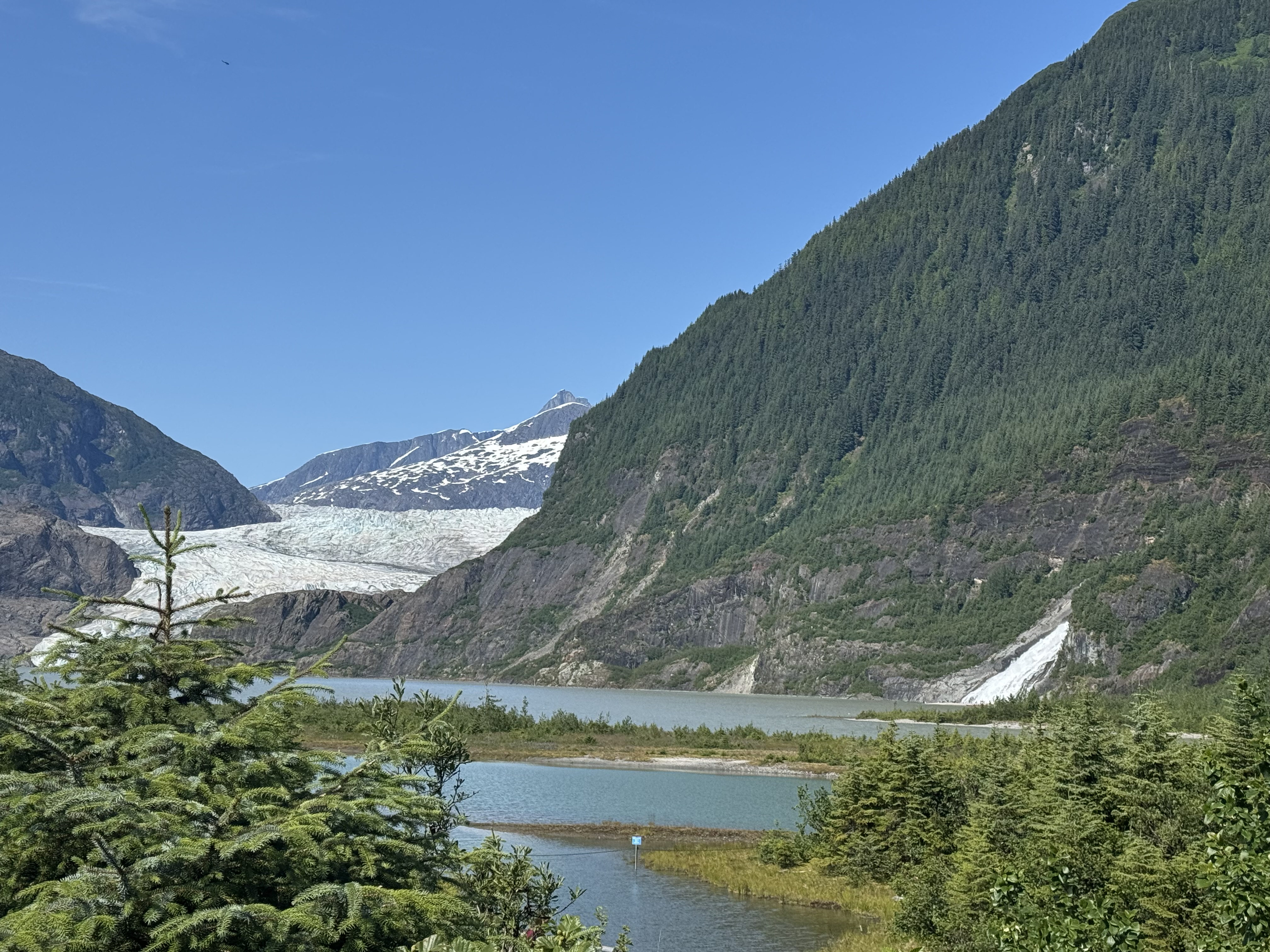 Mendenhall Glacier above Mendenhall Lake with a waterfall spilling down the mountain beside it