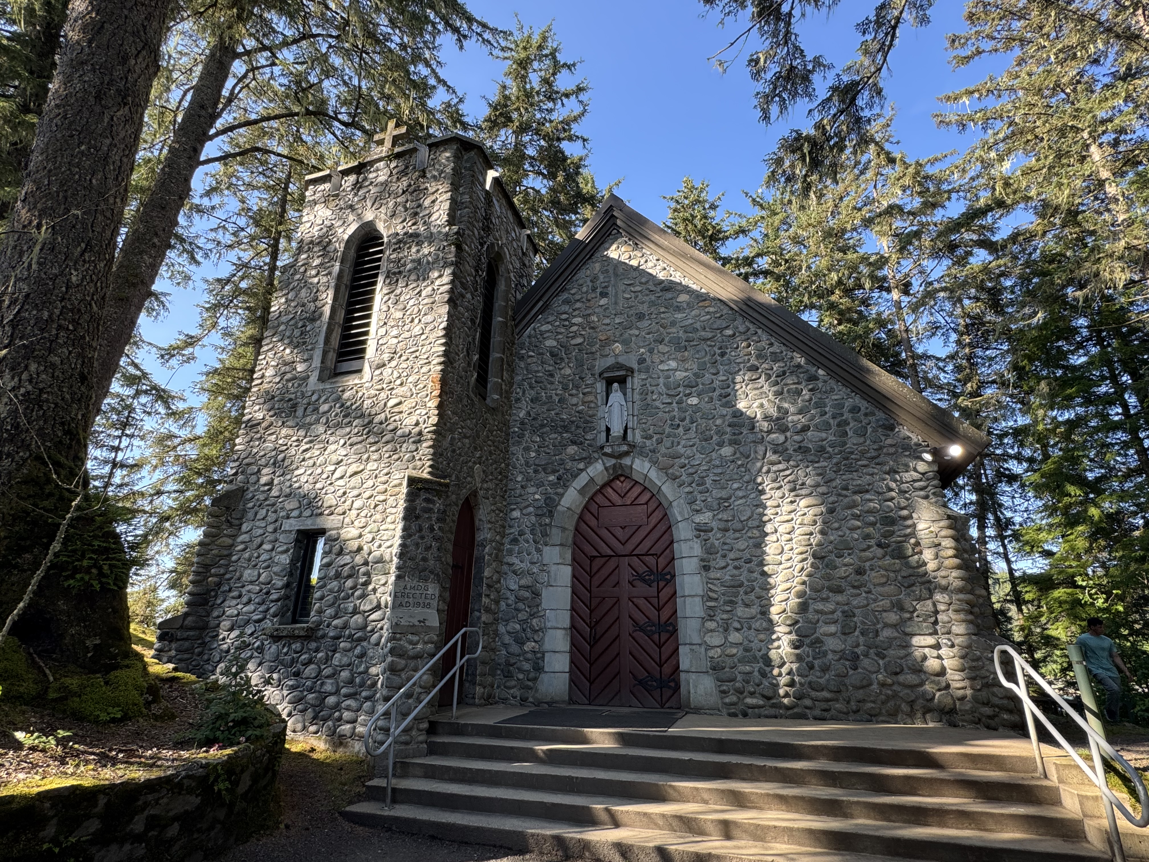 The stone chapel at the Shrine of St. Thérèse beneath tall evergreens near Juneau