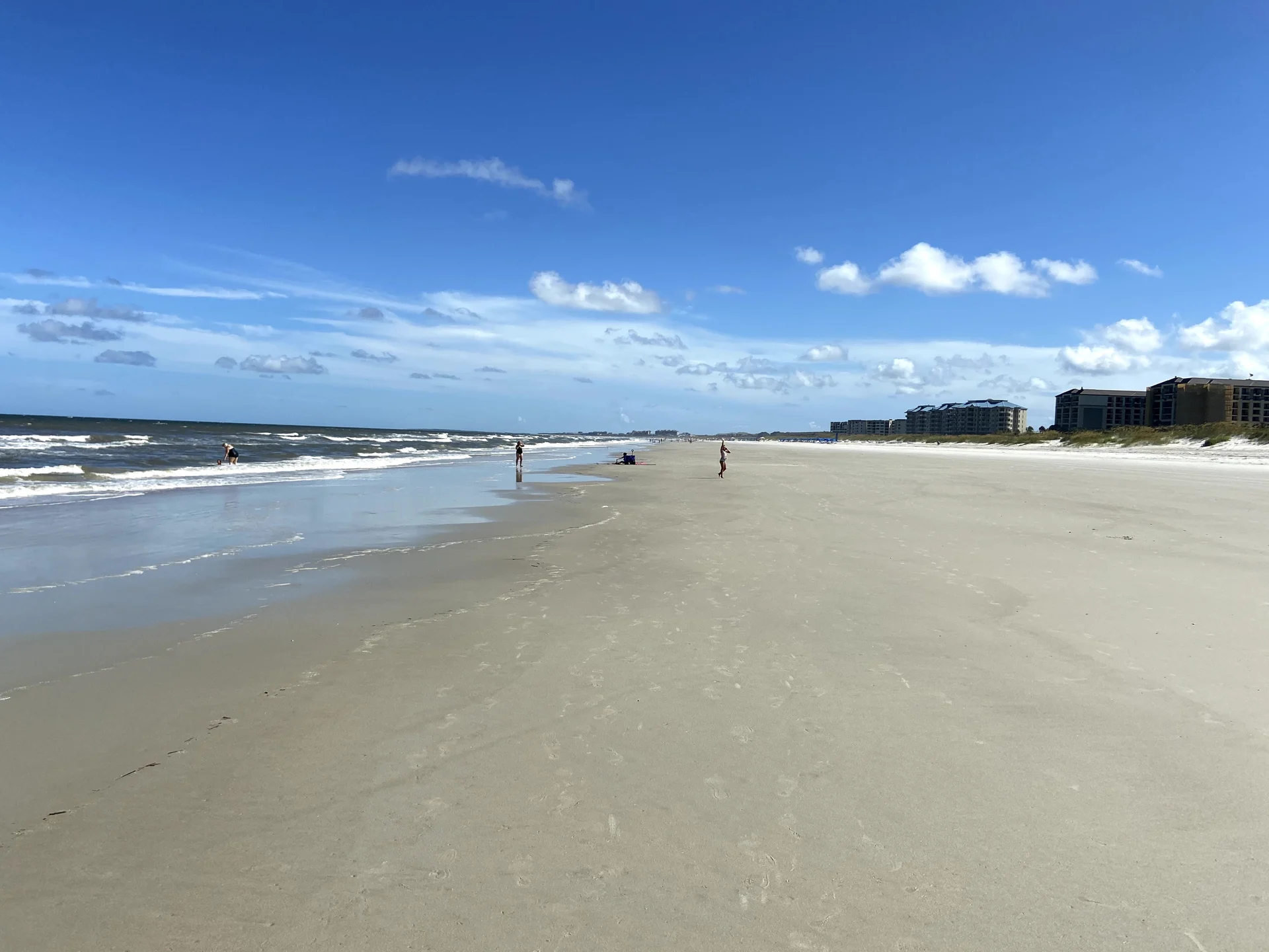 Wide sandy Amelia Island beach with gentle Atlantic waves and only a few people in the distance in July 2020