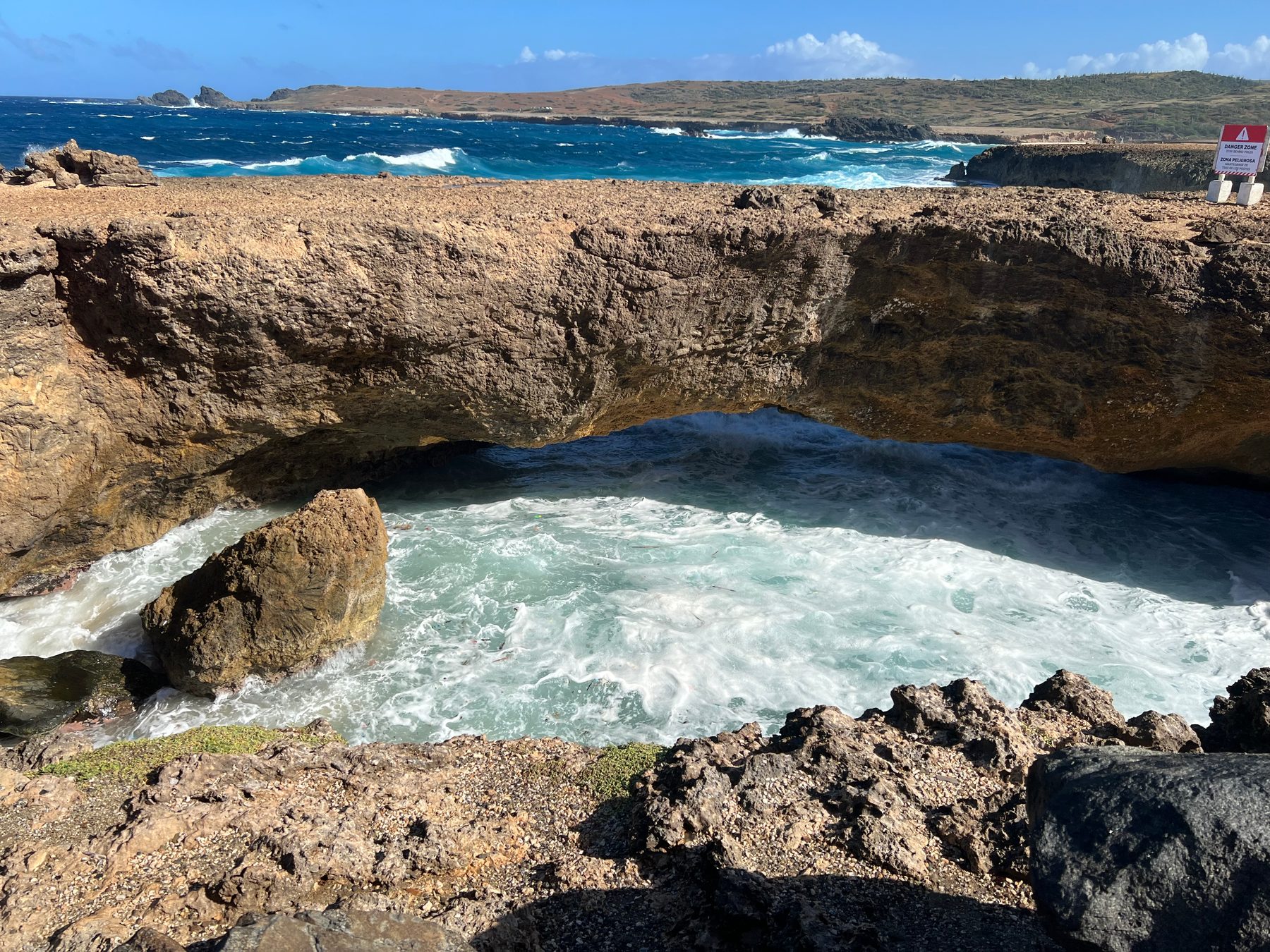 A small natural sea arch above rough water on Aruba's north coast