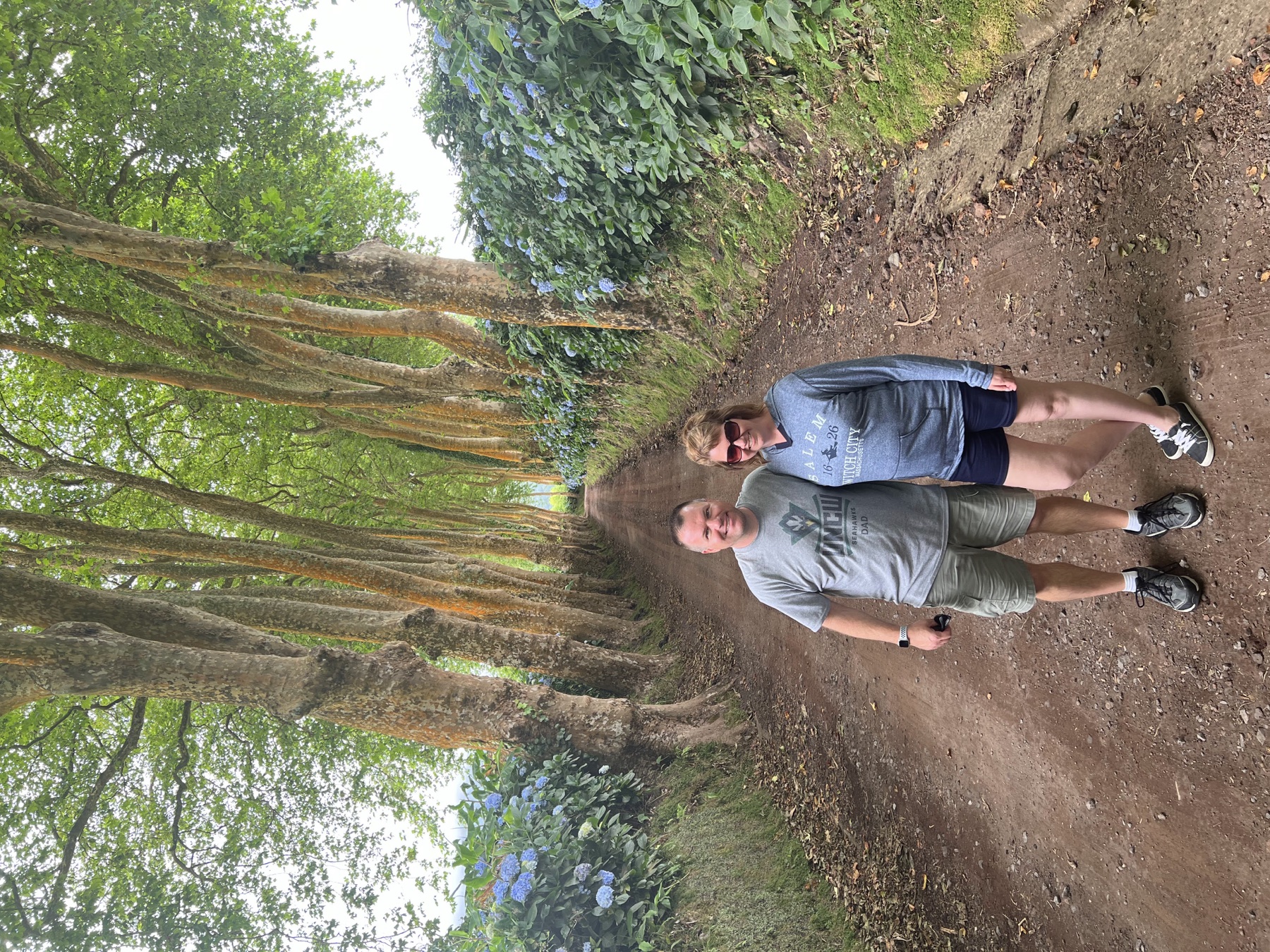 Angela and Brian walking together on a shaded dirt path lined with tall trees