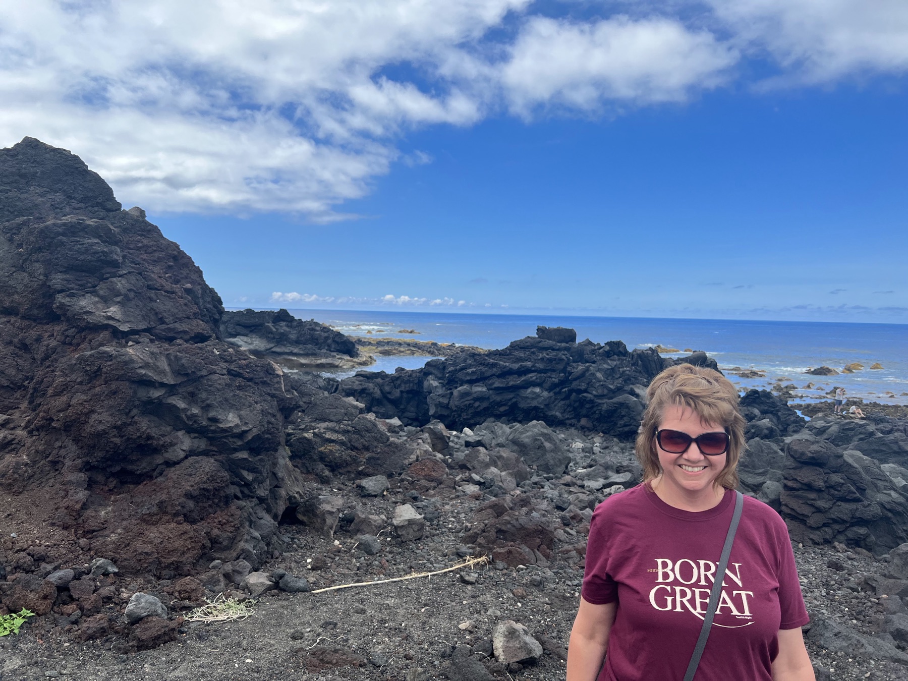 Angela standing beside dark volcanic rocks at Mosteiros on São Miguel’s west coast