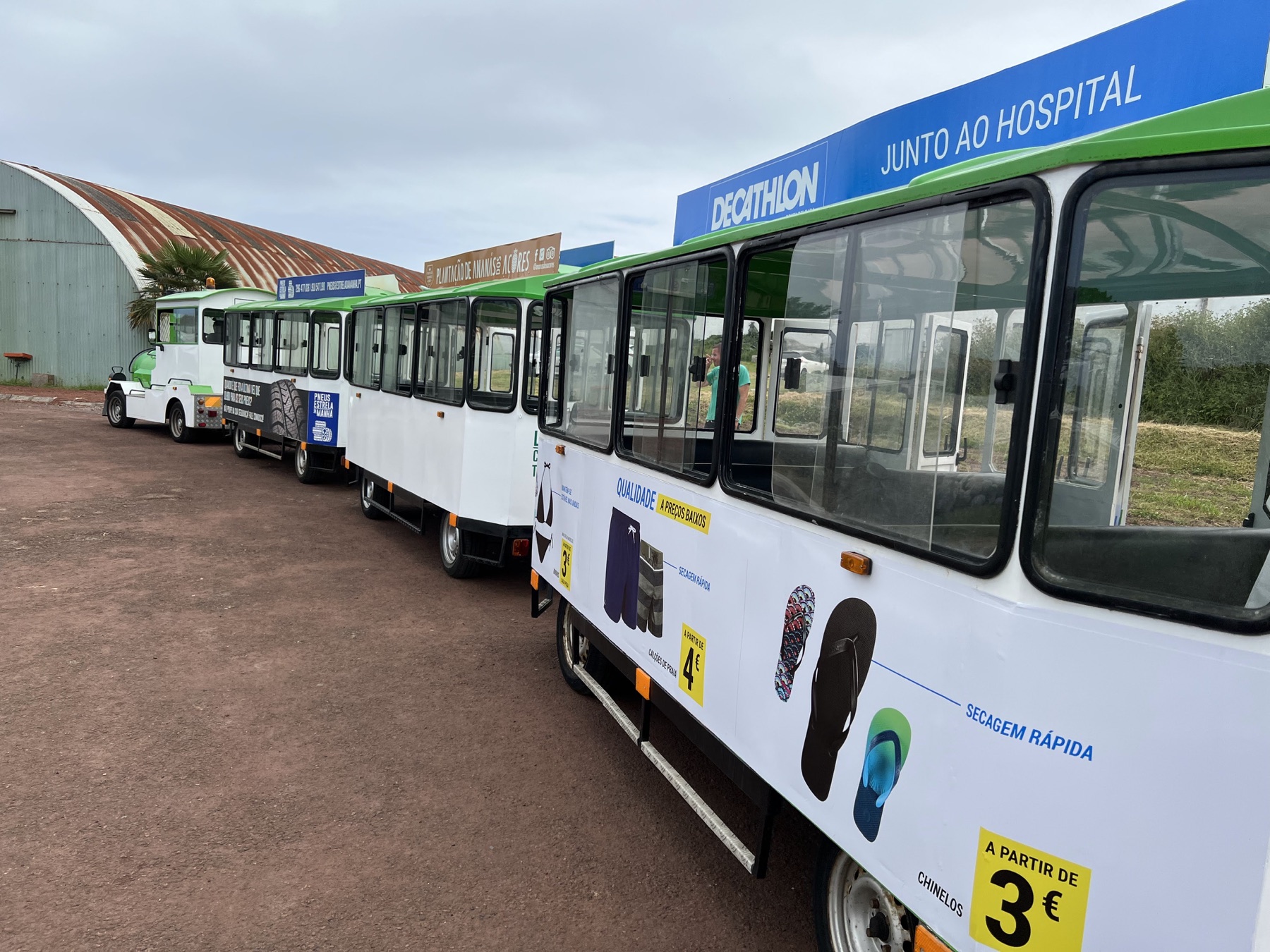 White open-sided tourist tram parked outside a pineapple plantation greenhouse