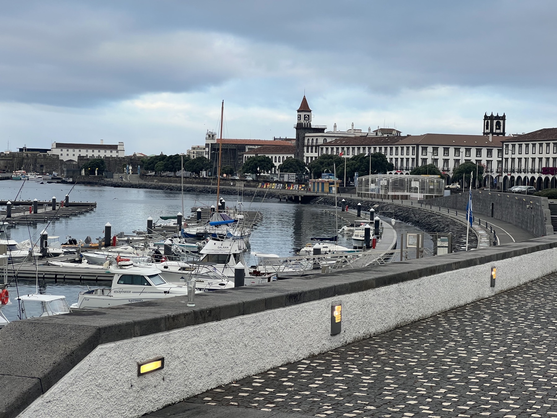 Boats in Ponta Delgada harbor with historic waterfront buildings beyond