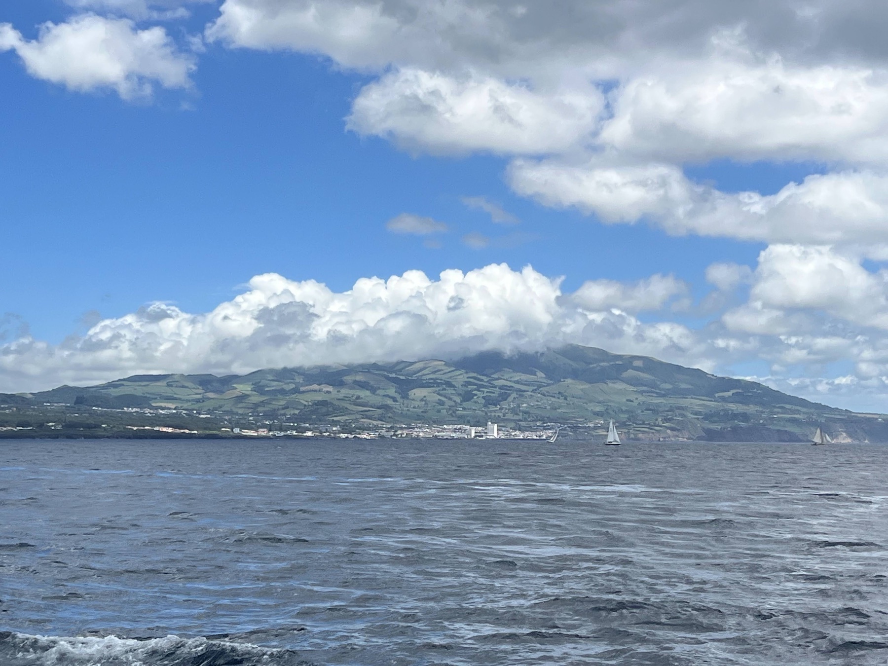 Green hills and shoreline of São Miguel viewed across the Atlantic from a whale-watch boat