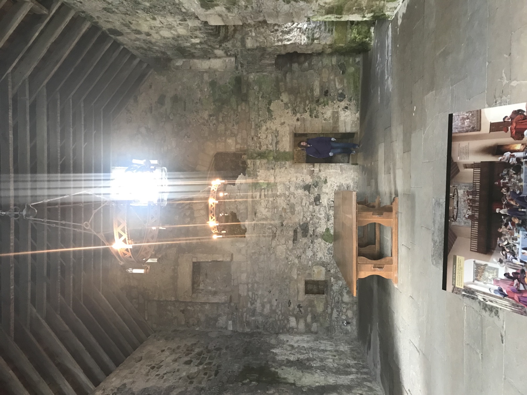 High stone room inside Blackness Castle with timber roof beams and chandeliers