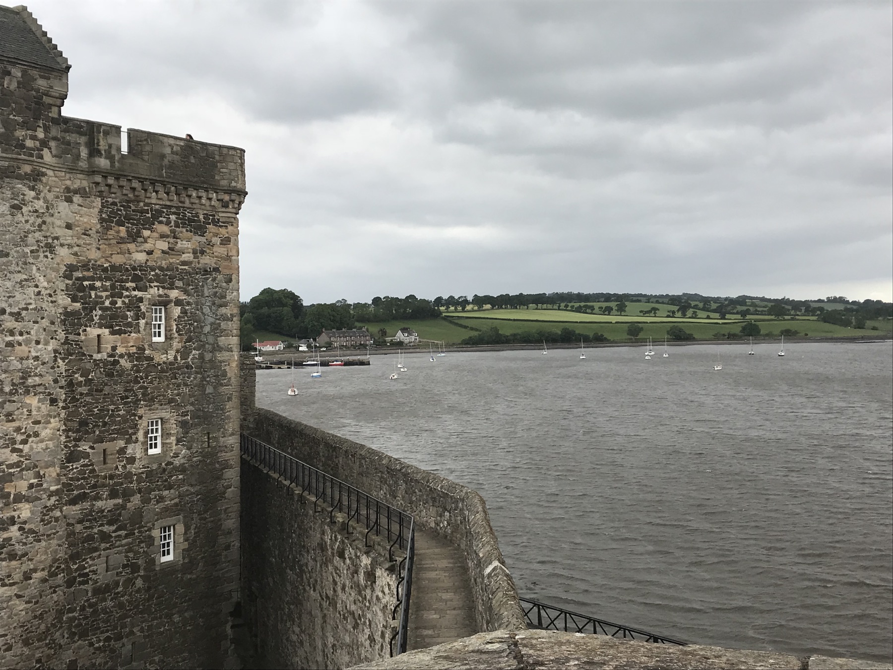 Blackness Castle wall overlooking boats on the Firth of Forth and green fields beyond