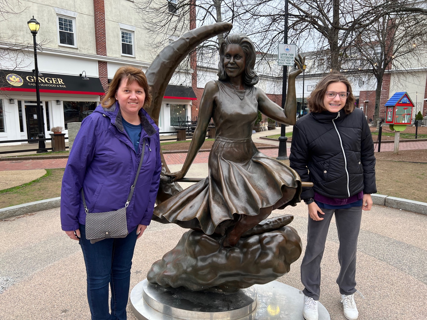Angela and a teenage daughter standing beside the Bewitched statue in Salem
