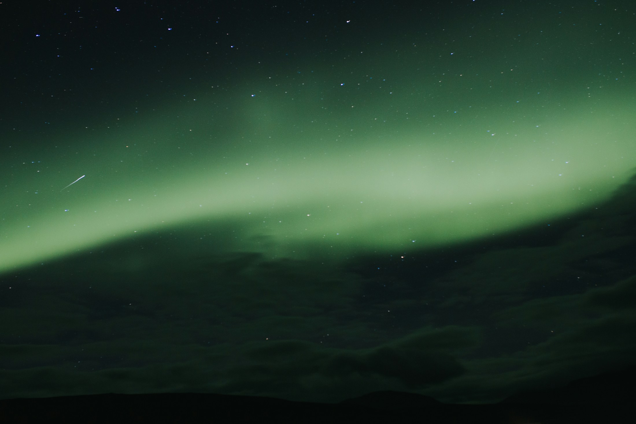 Green northern lights stretching across a dark, starry sky