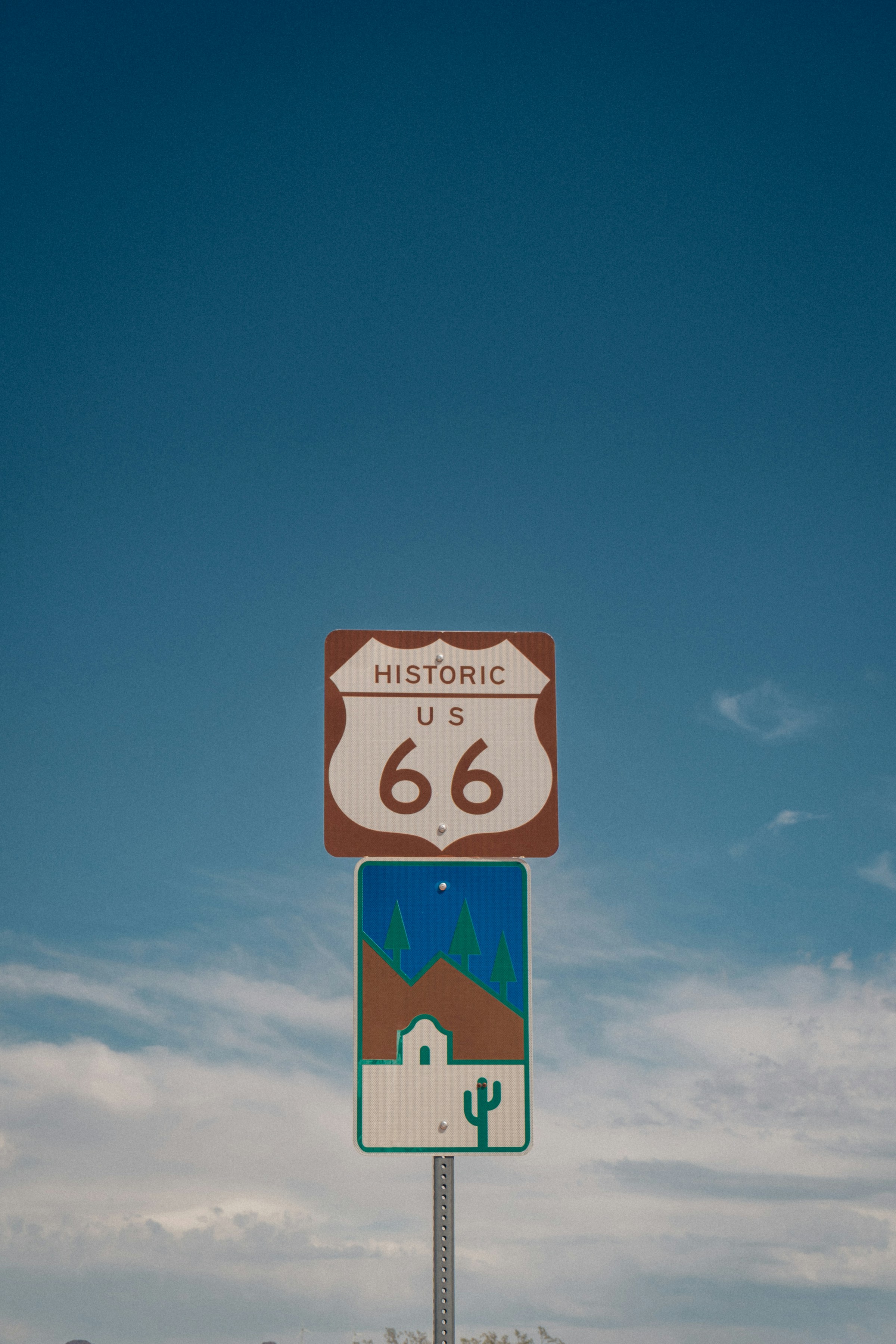 A Historic Route 66 road sign beneath a wide blue sky