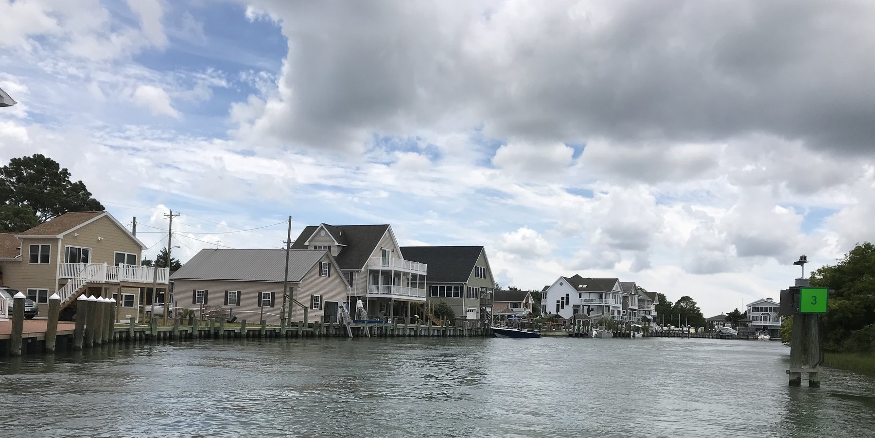Waterfront homes, docks, and boats lining a Chincoteague channel beneath dramatic clouds