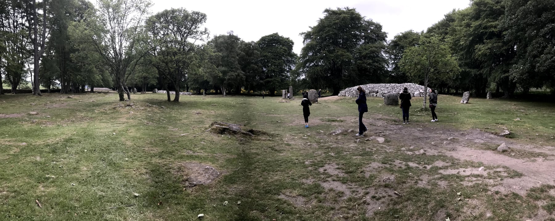 Visitors walking between the circular cairns and standing stones at Clava Cairns