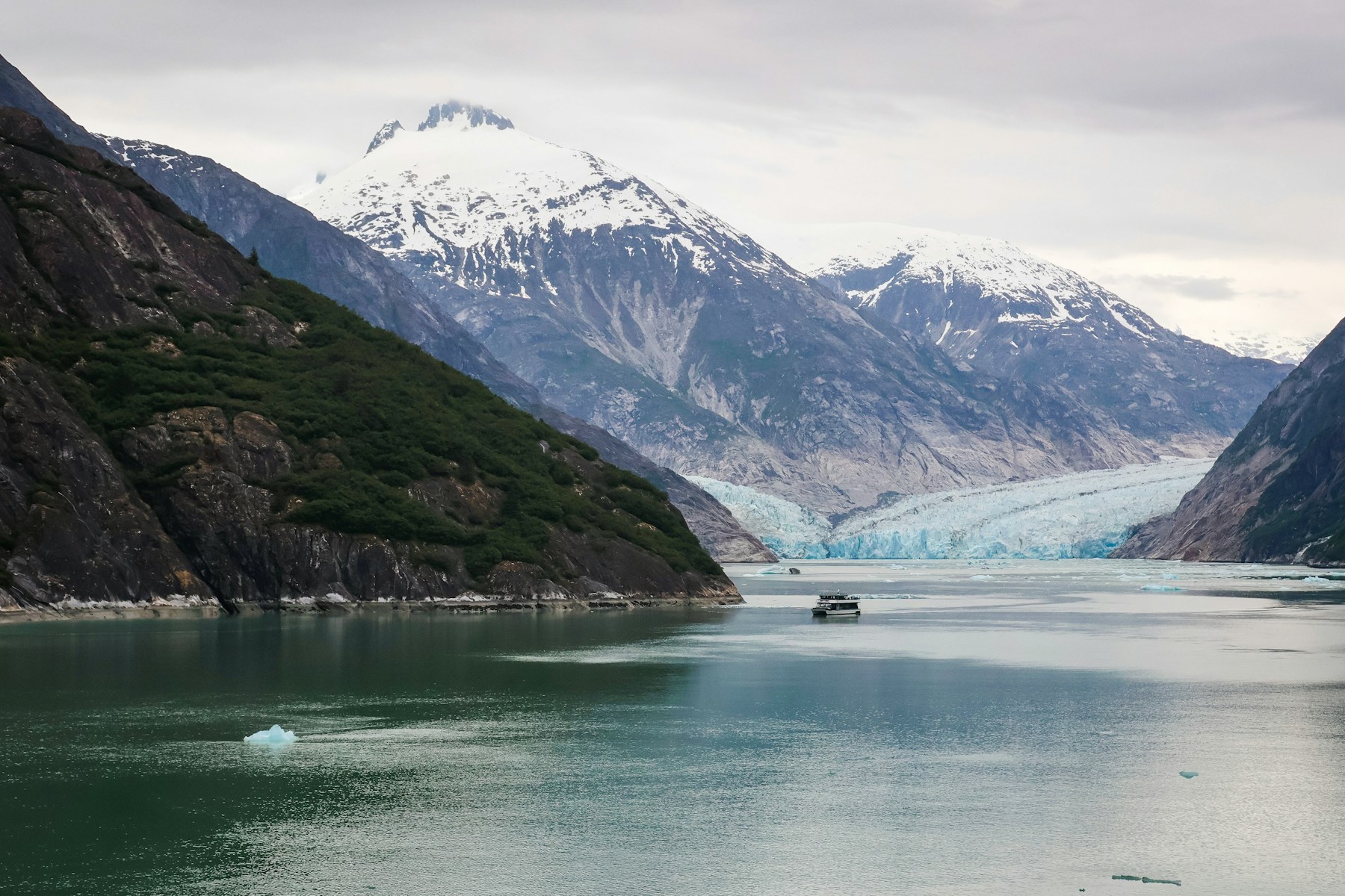 A cruise ship surrounded by mountains and water near Dawes Glacier in Alaska