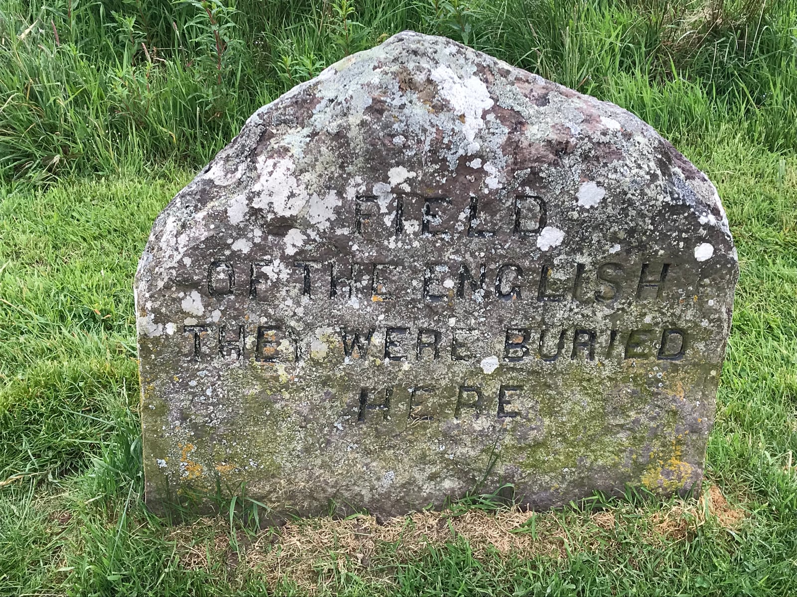 Weathered clan grave marker set into the grass at Culloden Battlefield