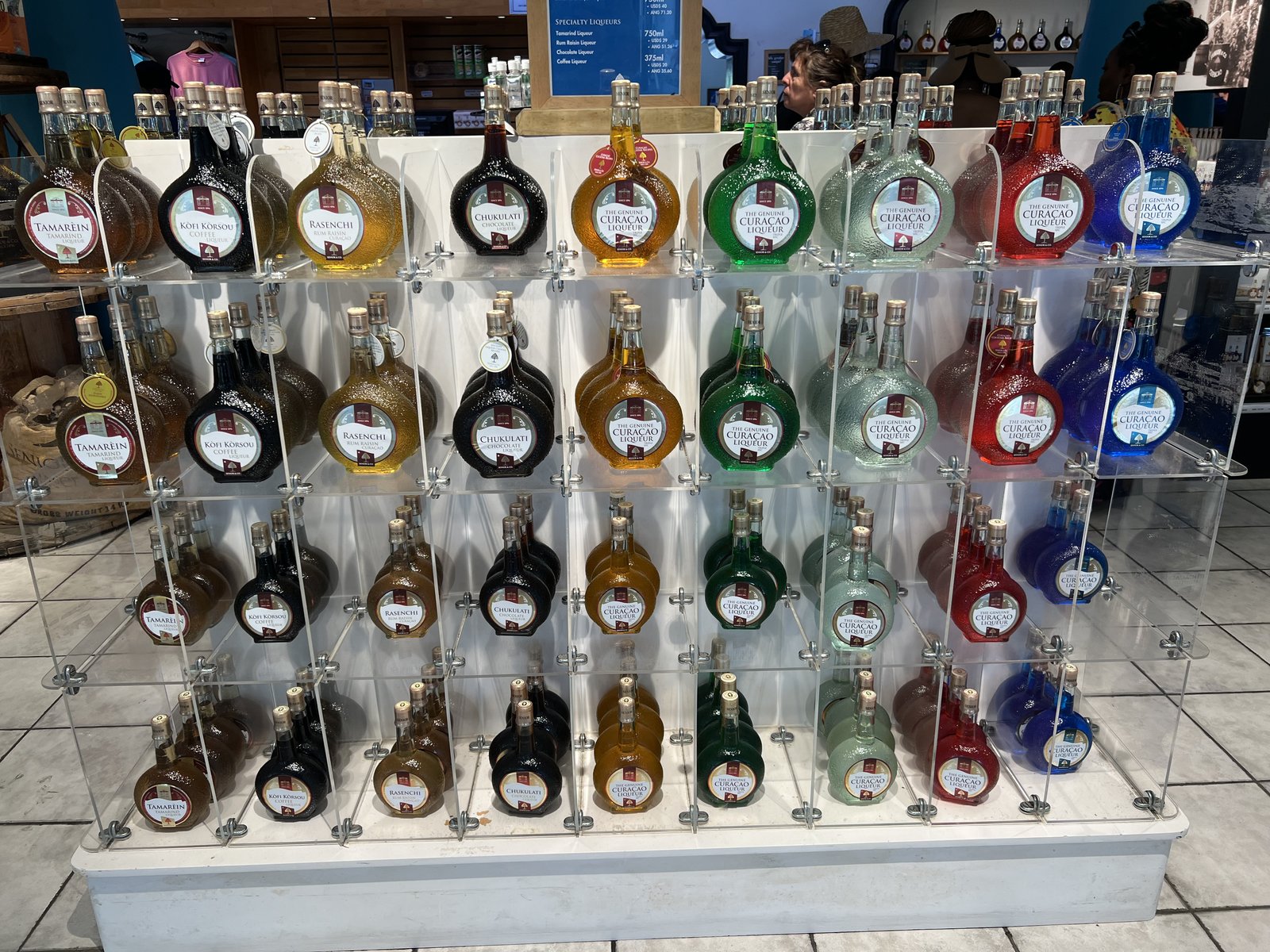 Rows of round Curaçao liqueur bottles in blue, orange, green, clear, and specialty flavors