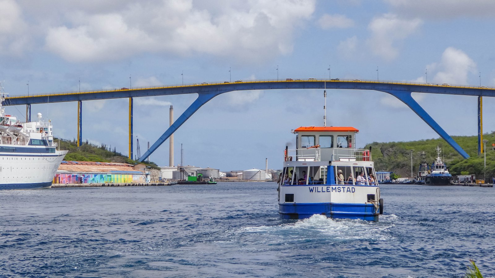 Queen Juliana Bridge arching over Sint Anna Bay with ships and a Willemstad ferry below