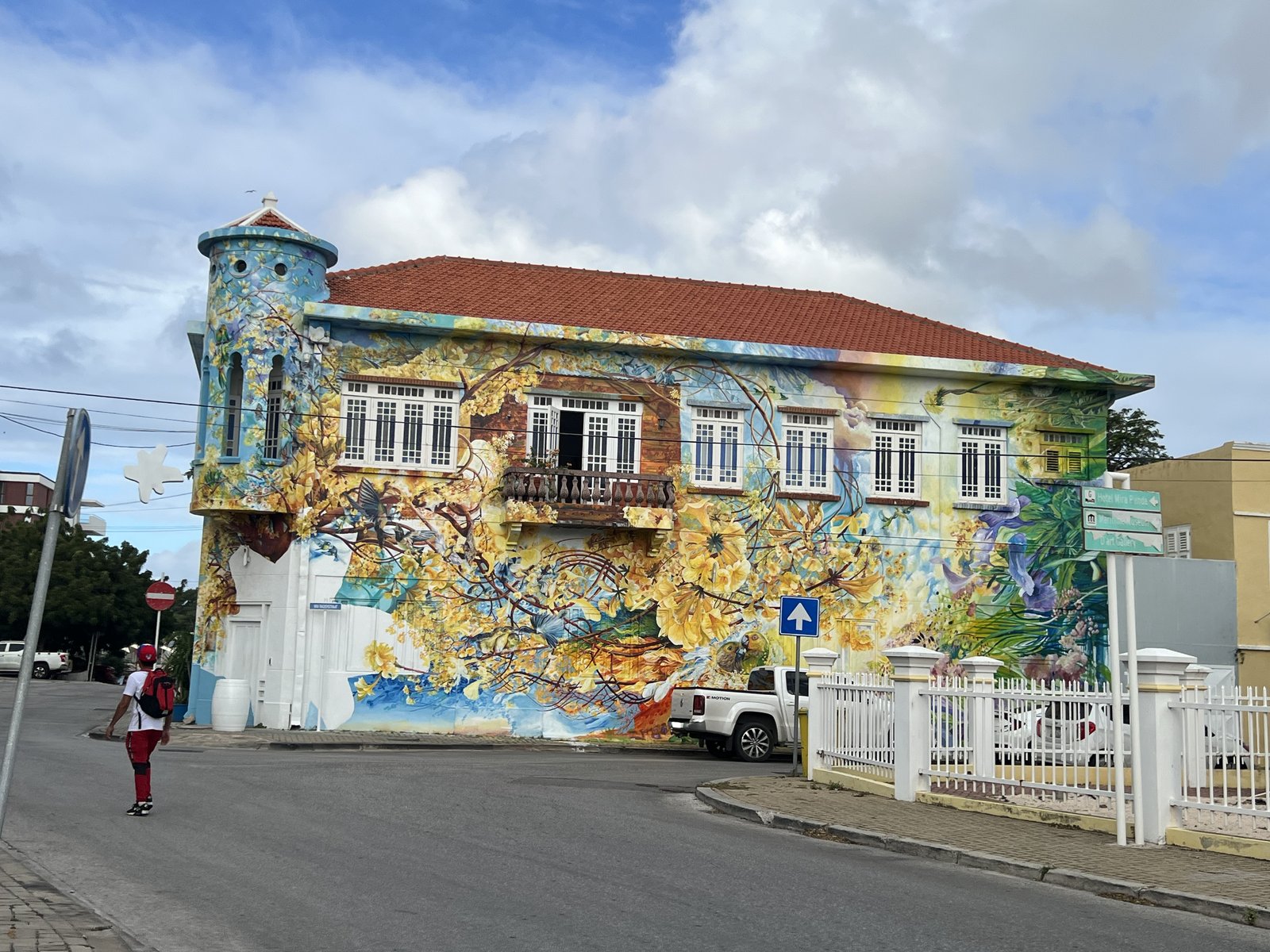 A Willemstad building covered in a colorful mural of flowers, birds, and branches