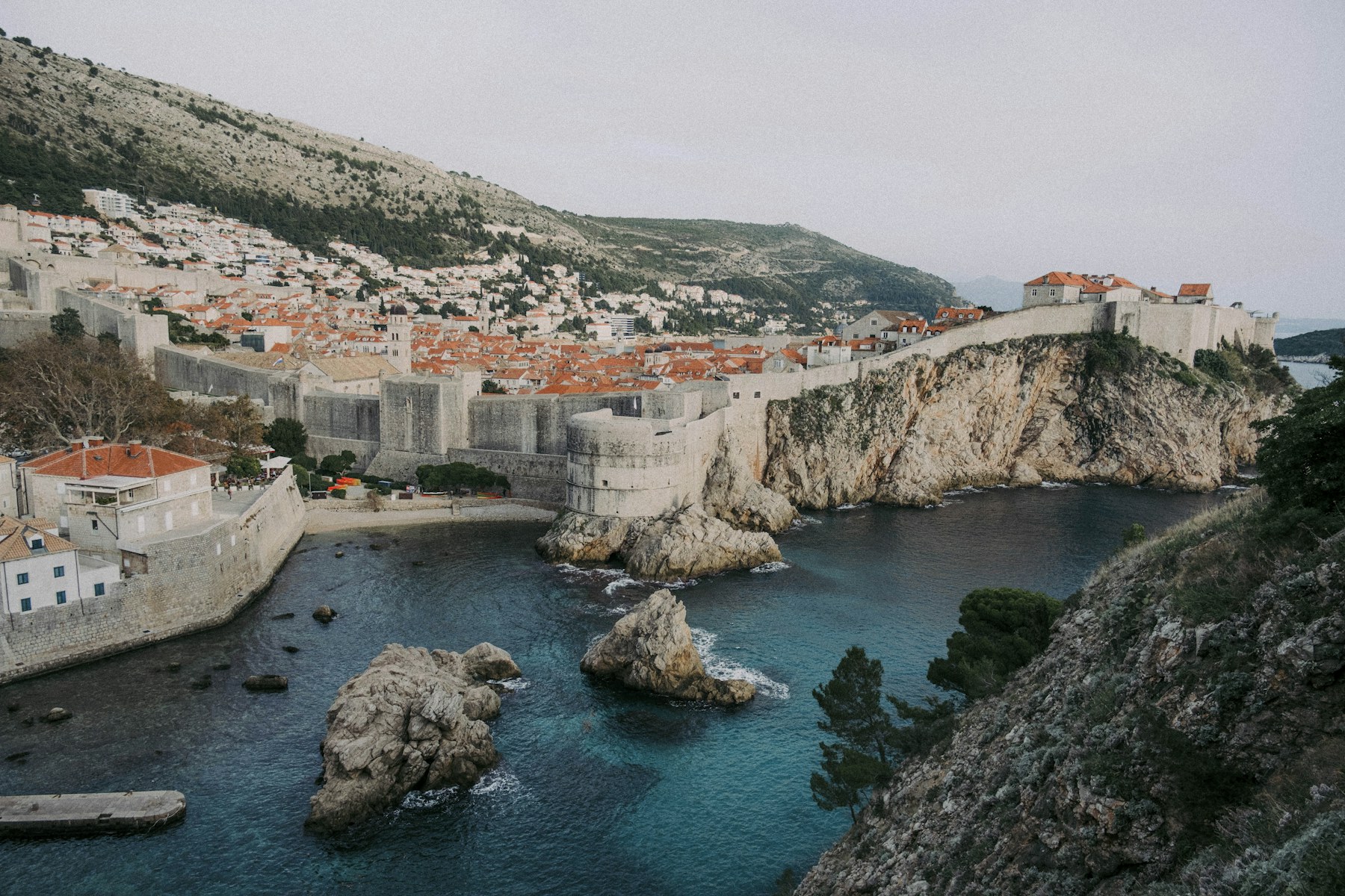 Dubrovnik’s stone city walls and red rooftops above a rocky Adriatic cove