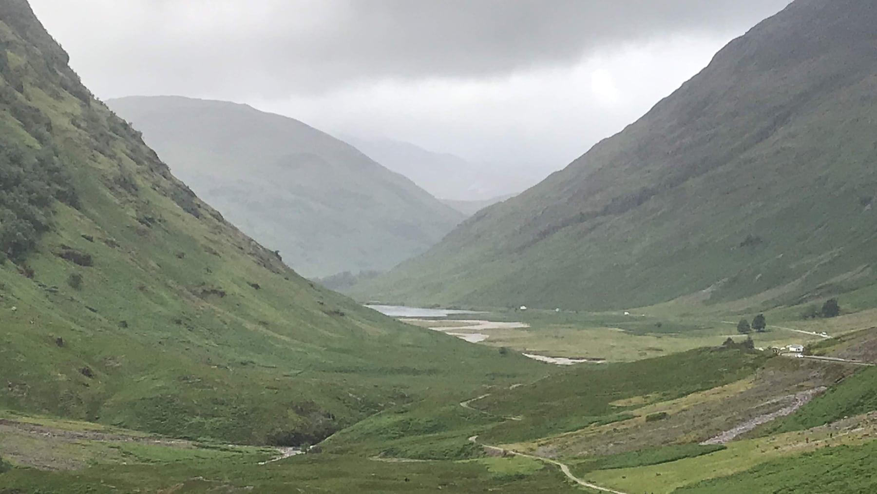 Glencoe valley receding between green mountains beneath low cloud