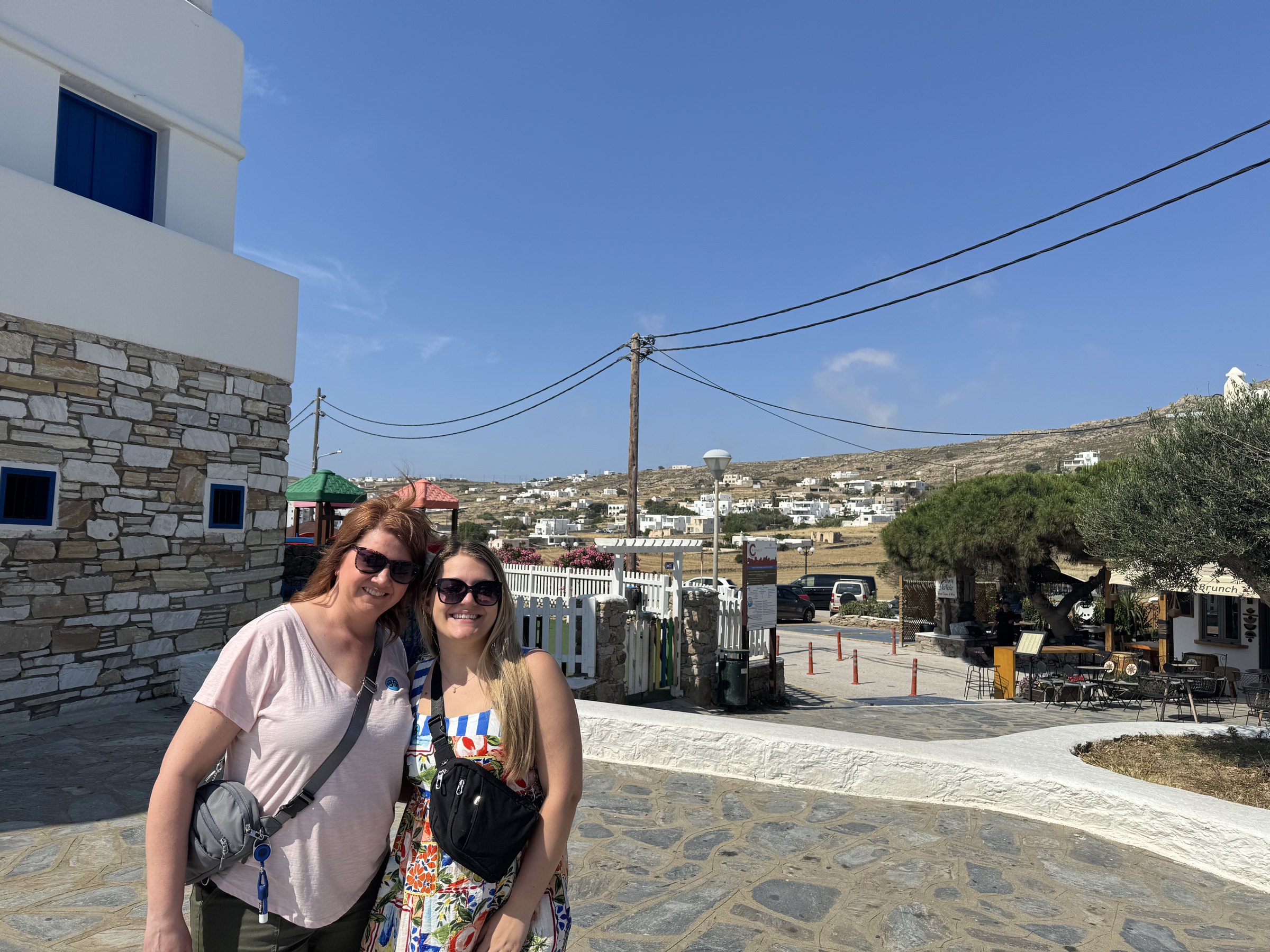 Angela and a family member standing beside a stone building during the stop at Ano Mera