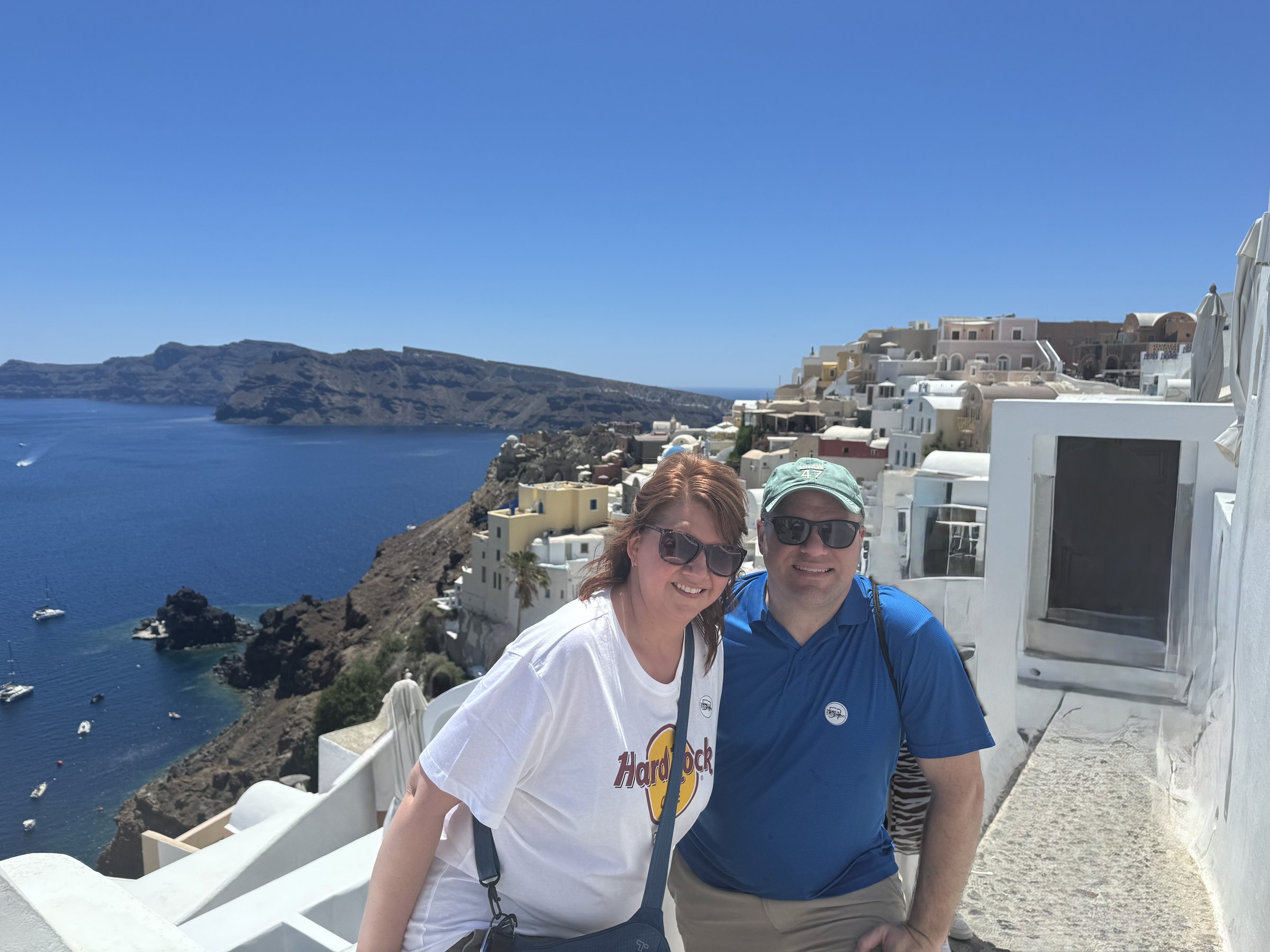 Two travelers looking across the caldera and whitewashed buildings in Oia