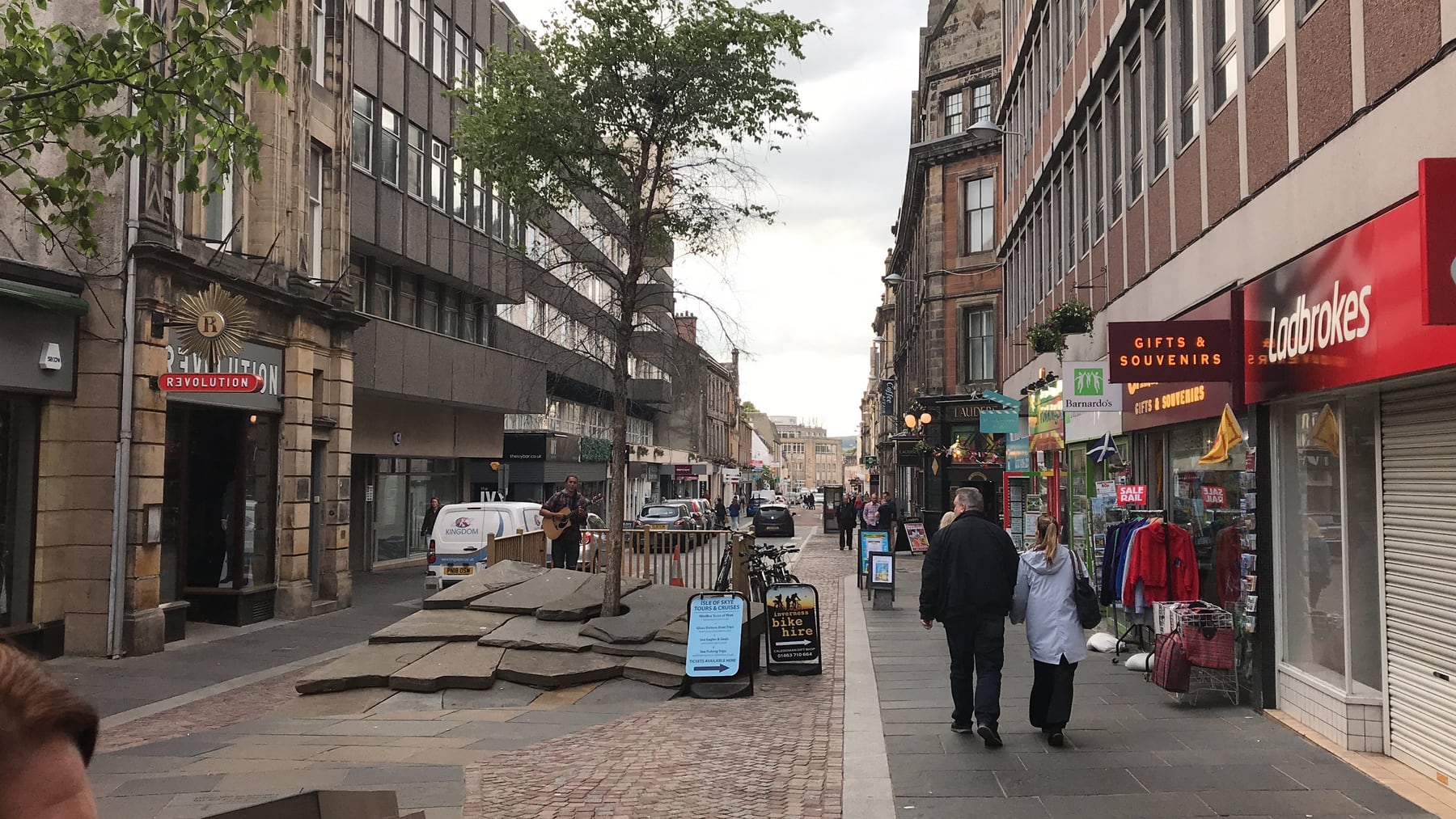 Pedestrians walking between shops on a central Inverness street