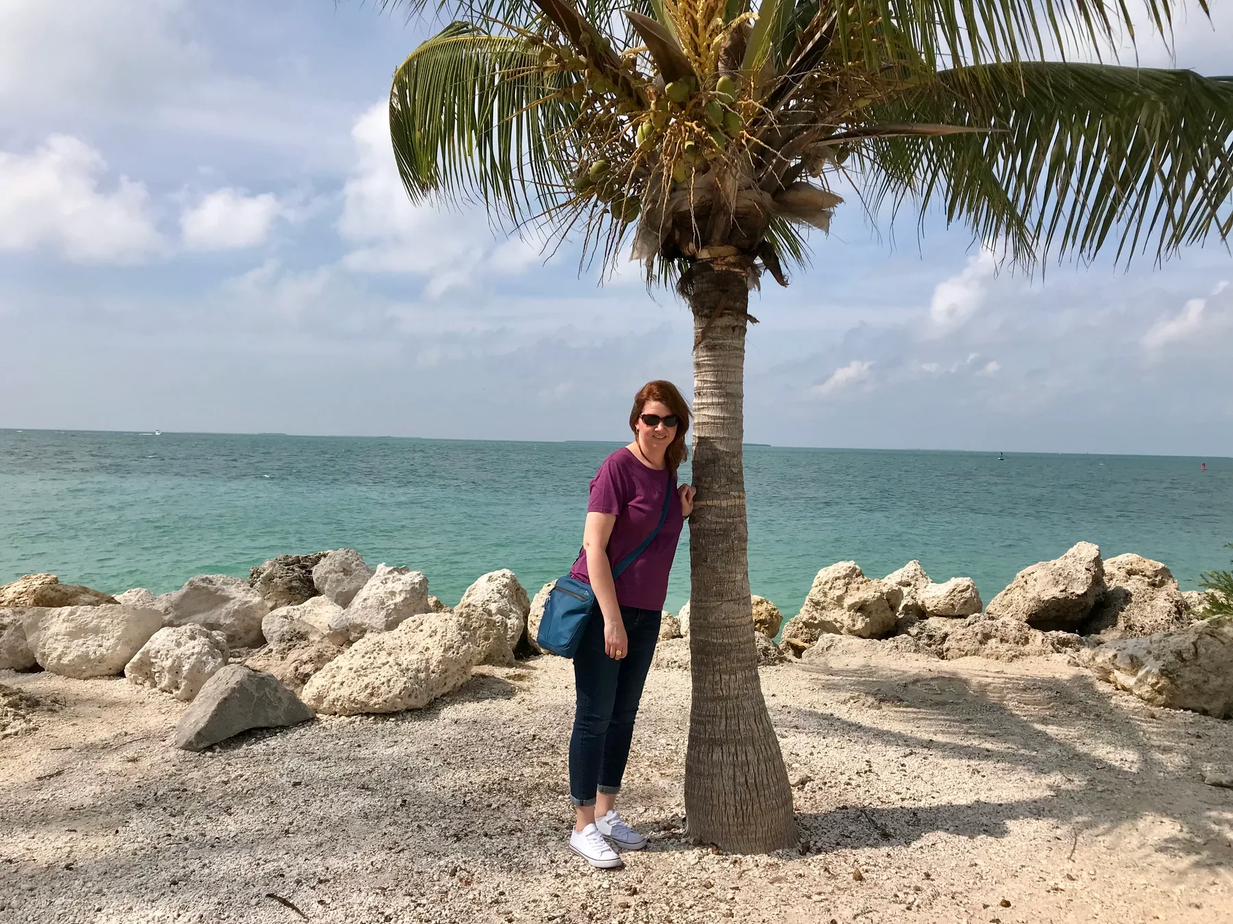 Angela standing beside a palm tree and turquoise water at Fort Zachary Taylor Historic State Park