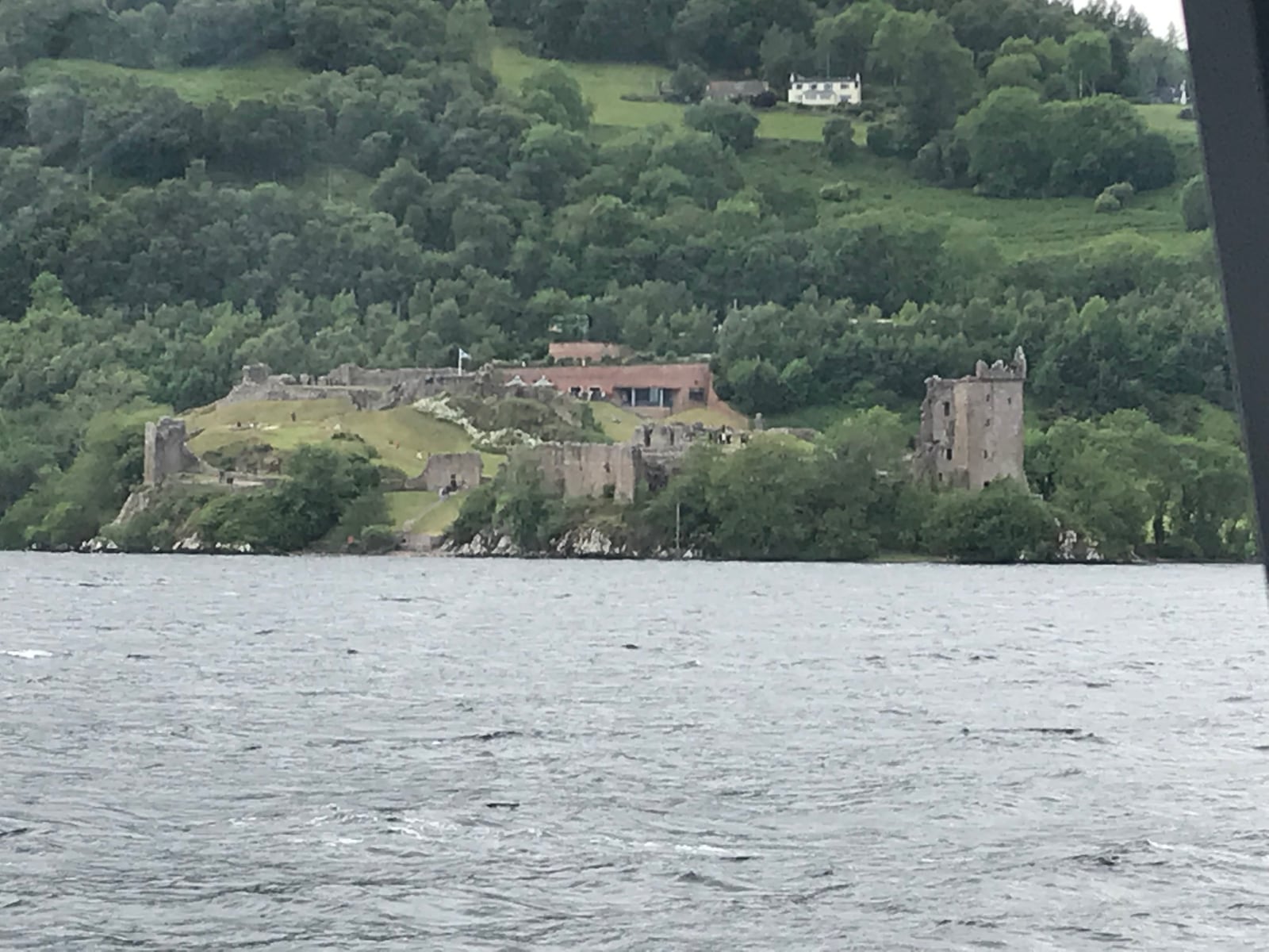 Ruins of Urquhart Castle on a wooded point above Loch Ness