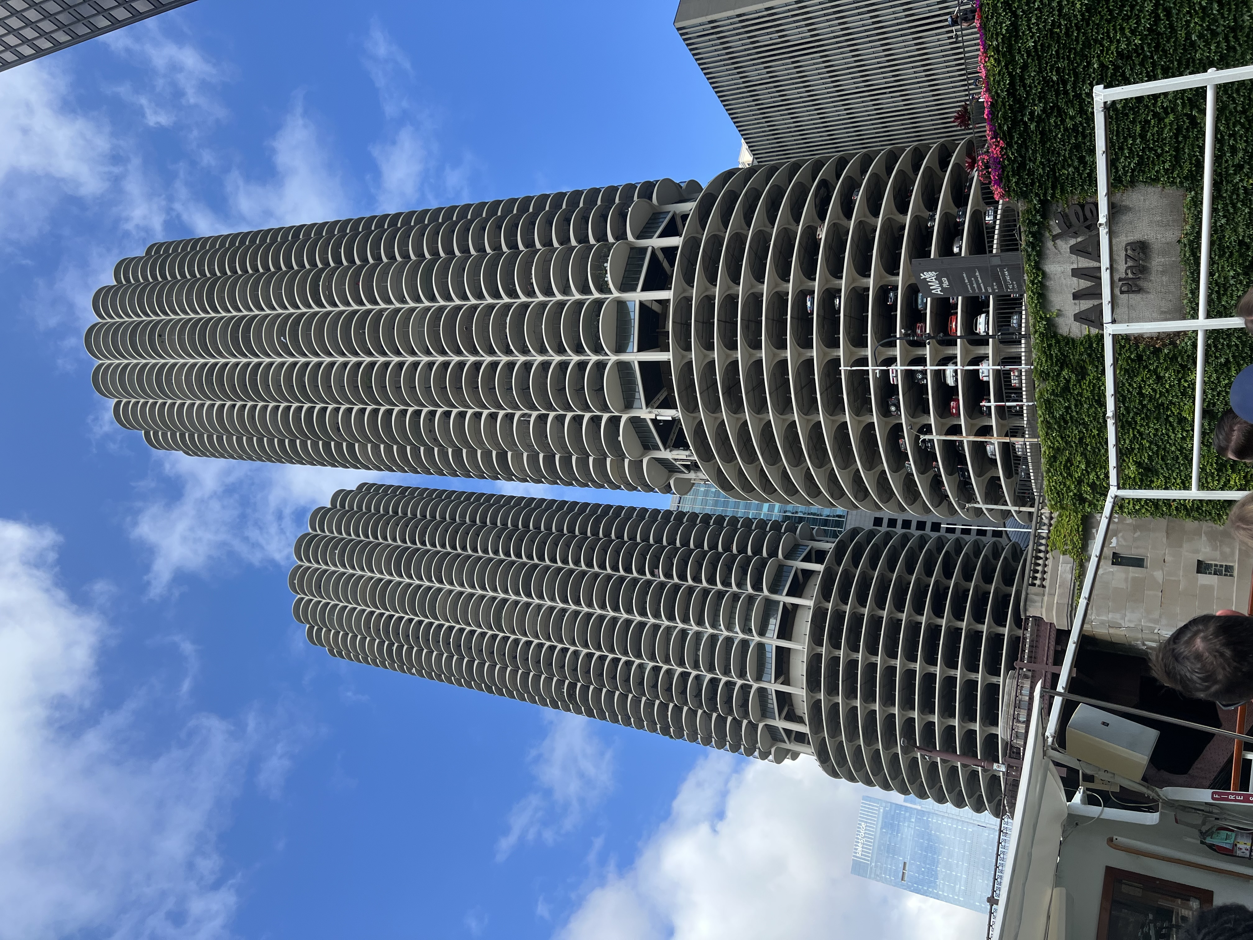 Angela sitting at an outdoor table on the Chicago Riverwalk with skyscrapers and Marina City behind her
