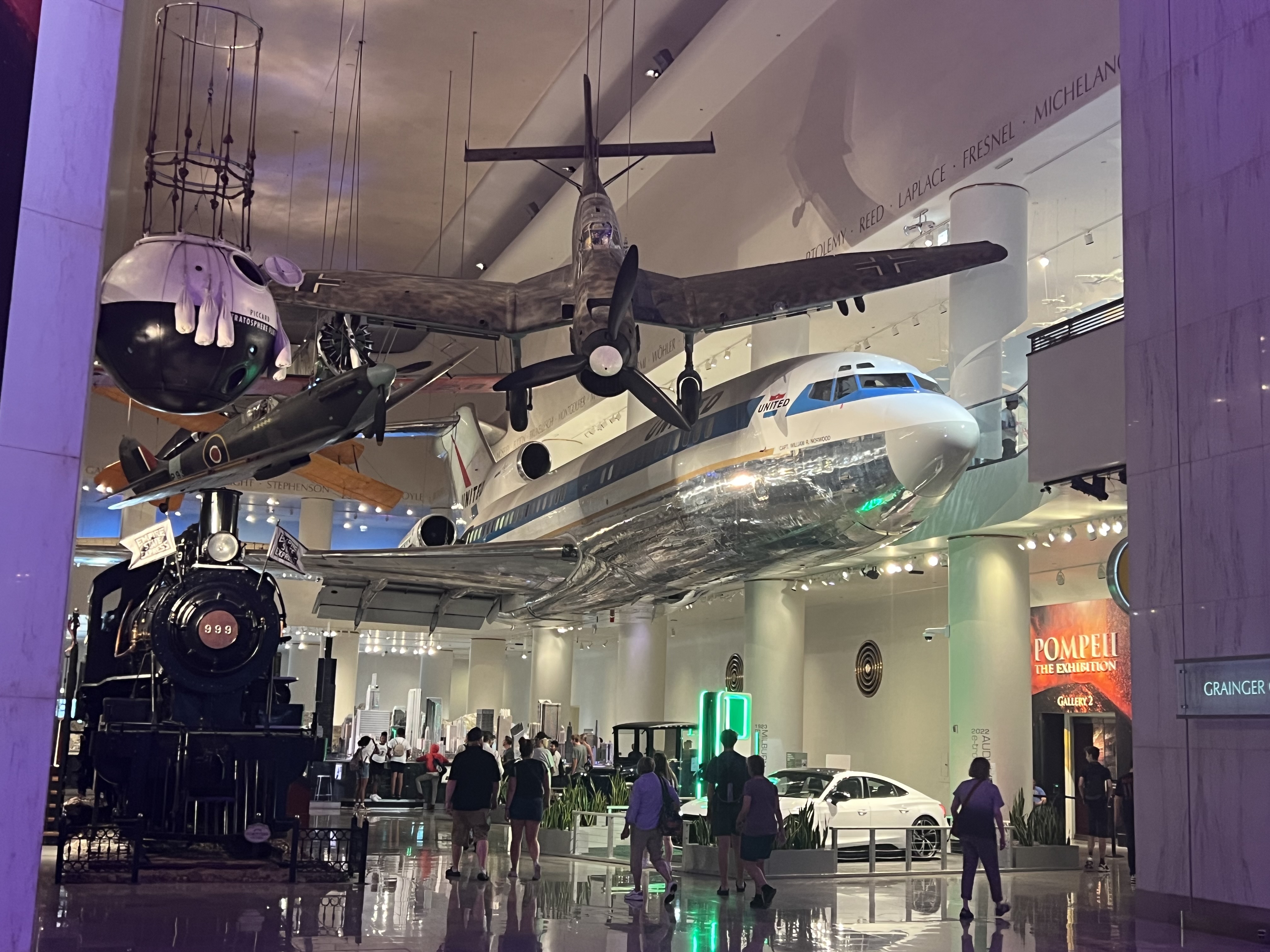 Historic train, aircraft, and a United airliner displayed in the Museum of Science and Industry's transportation hall