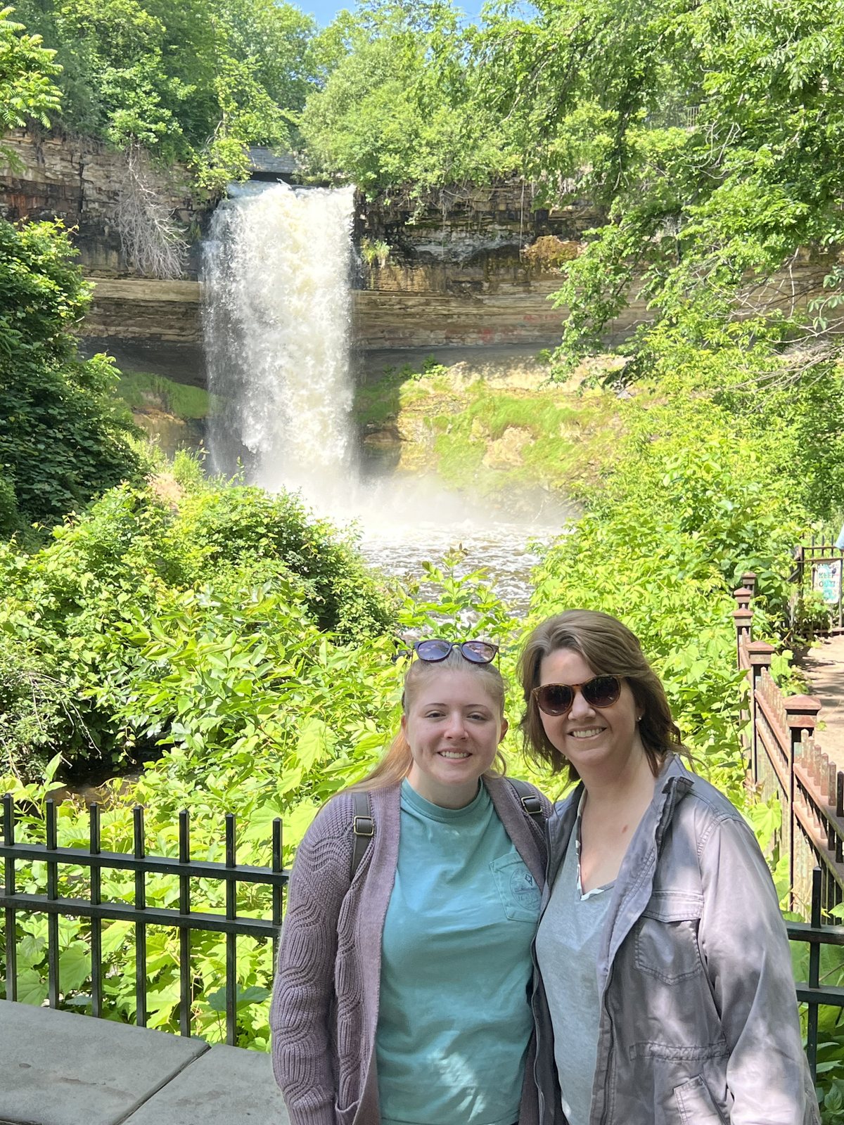 Minnehaha Falls spilling over a limestone ledge behind Angela and Madison