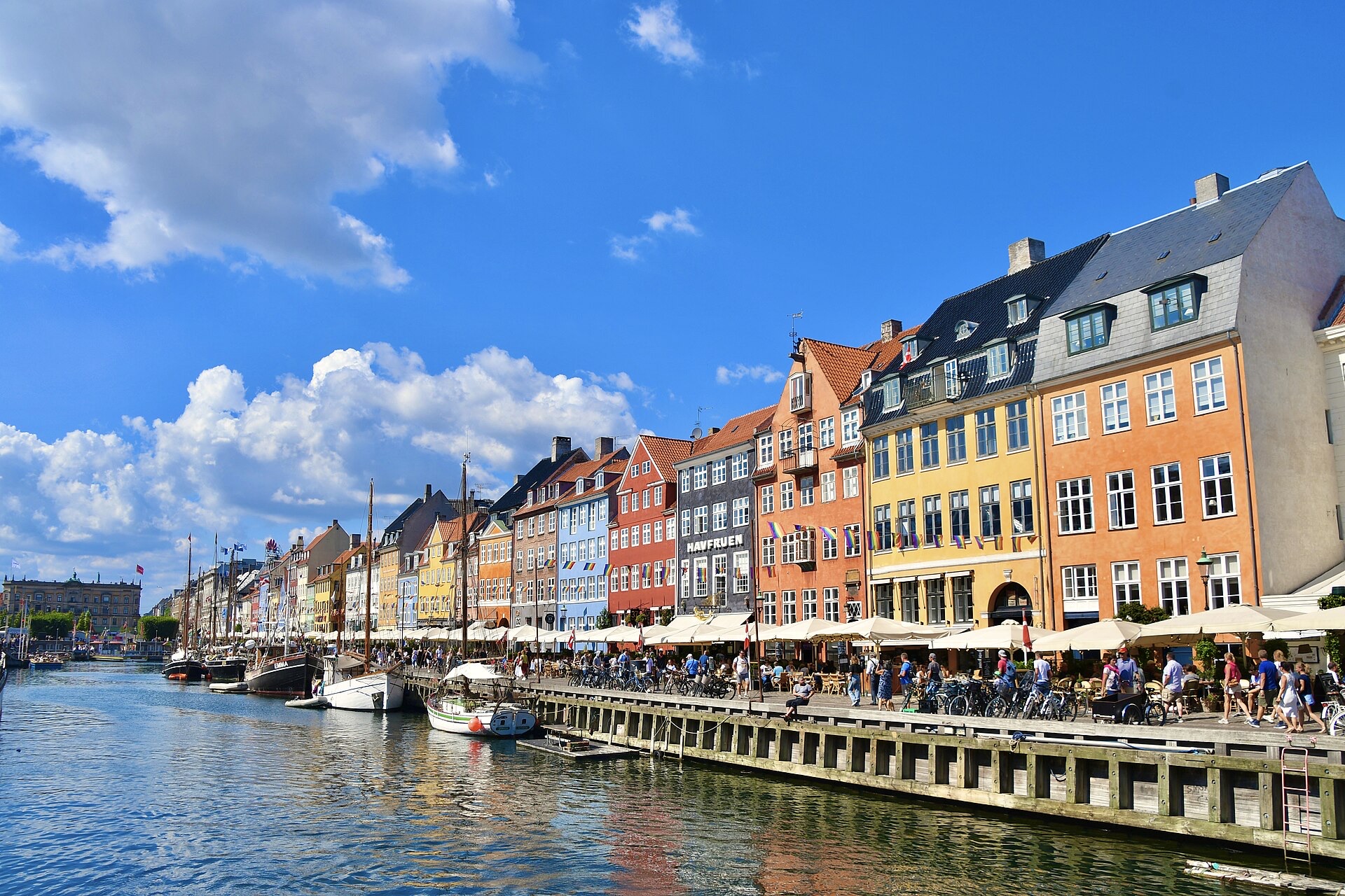 Colorful historic buildings, boats, and outdoor cafés along Nyhavn in Copenhagen