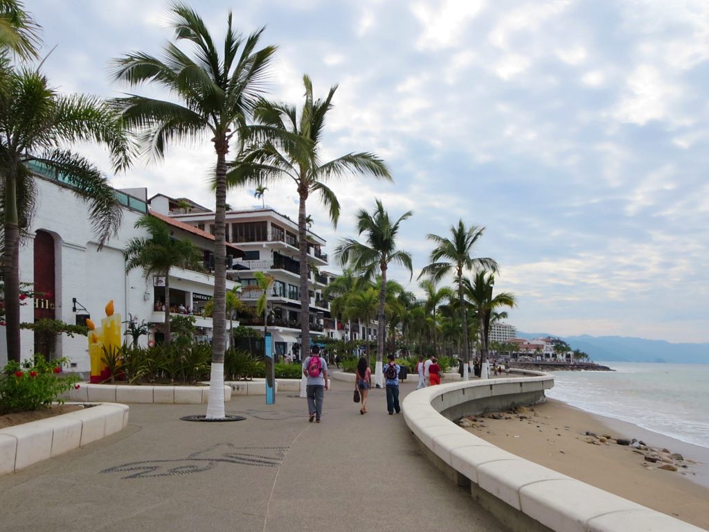Palm trees, sculptures, and pedestrians along the seaside Malecón in Puerto Vallarta