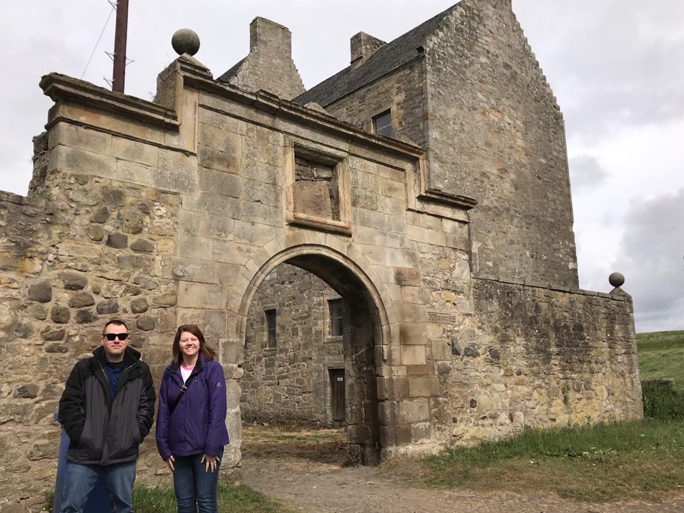 Angela and Brian standing in front of the arched gateway at Midhope Castle