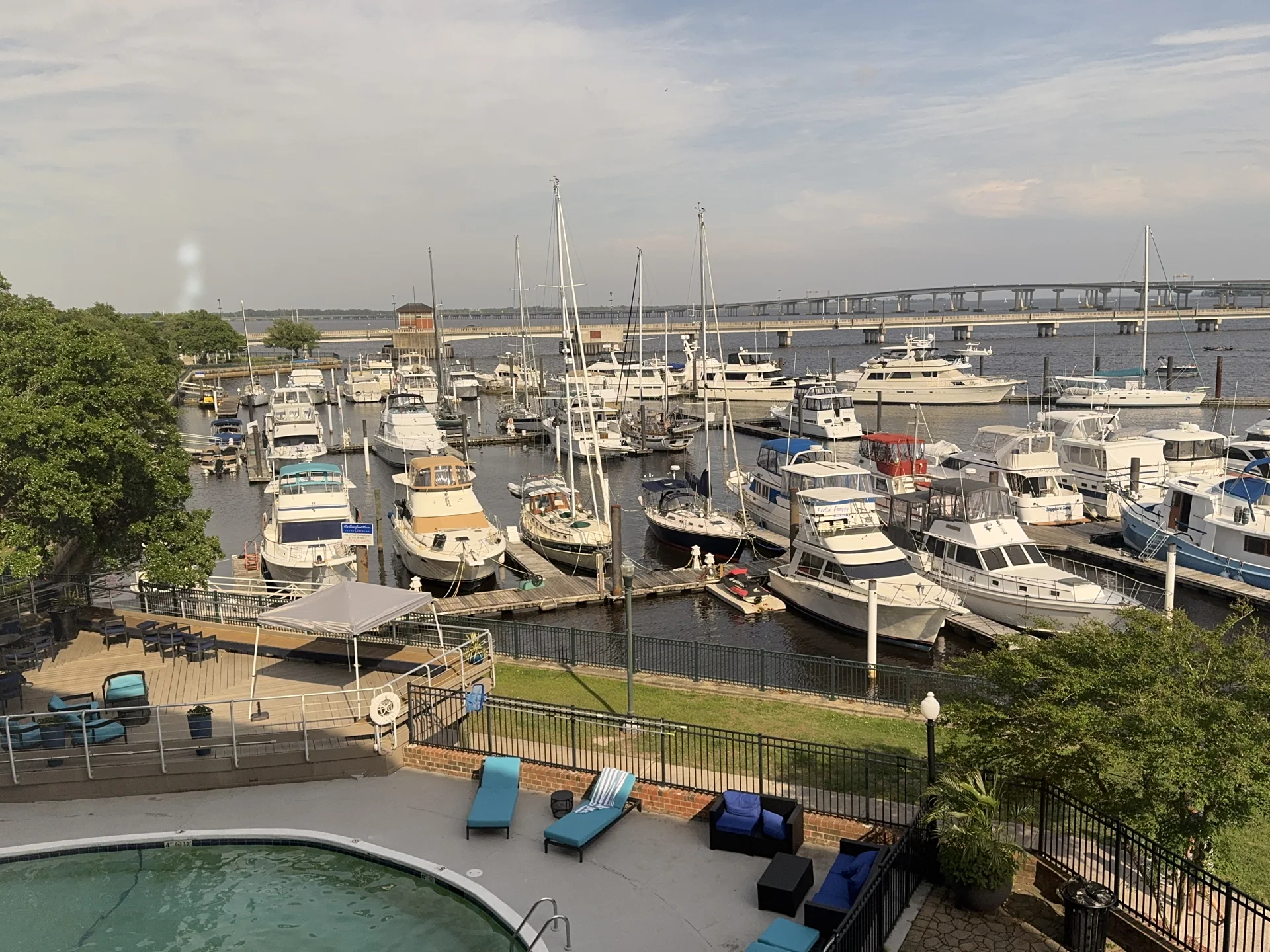 Boats in a New Bern marina, with a pool in the foreground and a bridge across the water beyond
