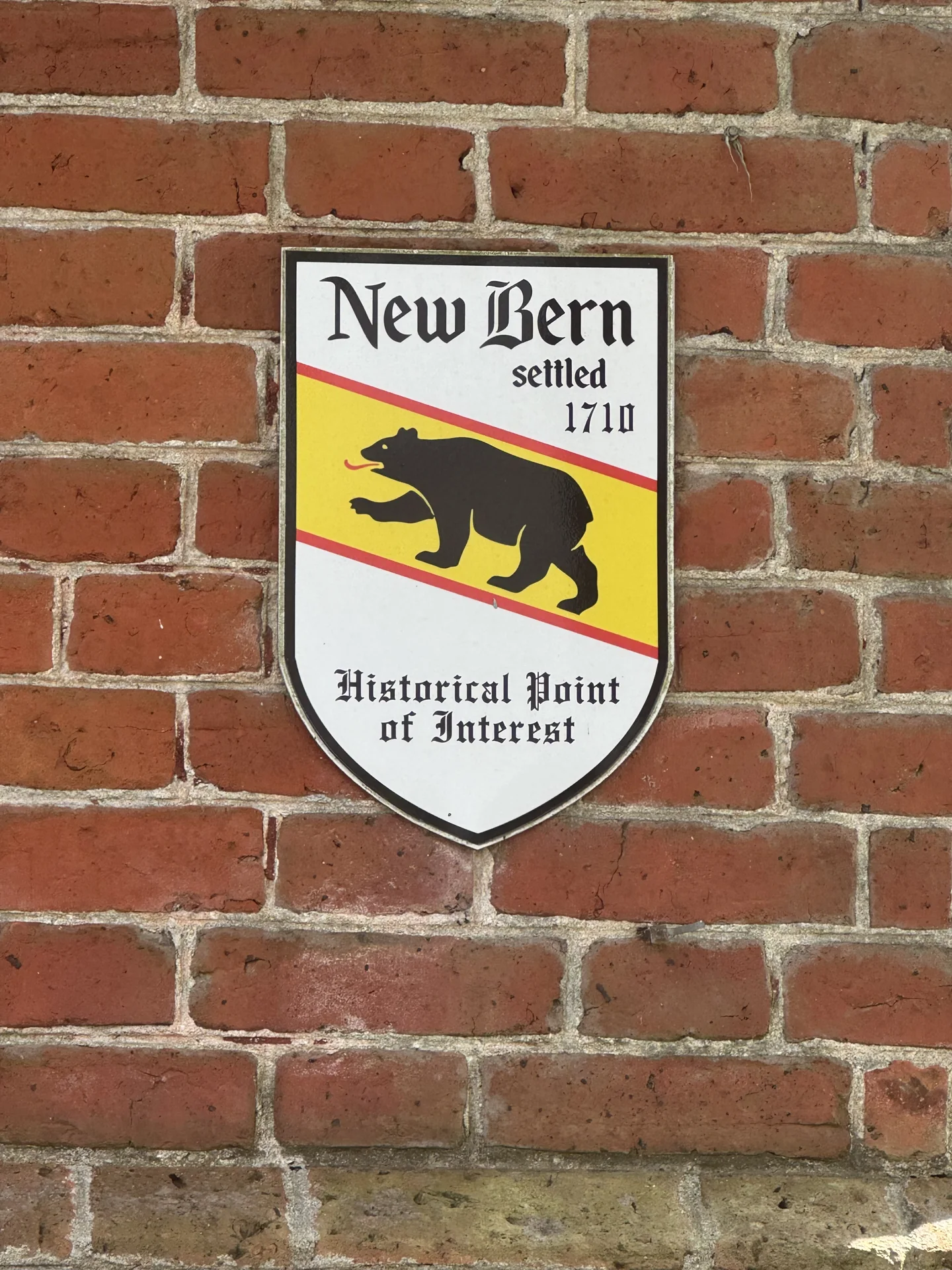 A New Bern historical point of interest plaque with a black bear and the date 1710 on a brick wall