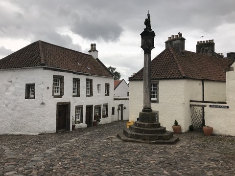 Whitewashed historic buildings and the stone Mercat Cross in Culross