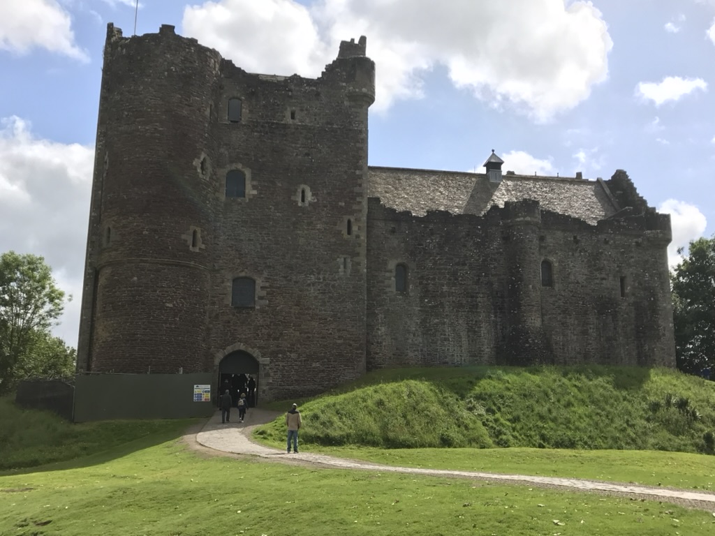 The stone towers and entrance of Doune Castle beneath a bright sky